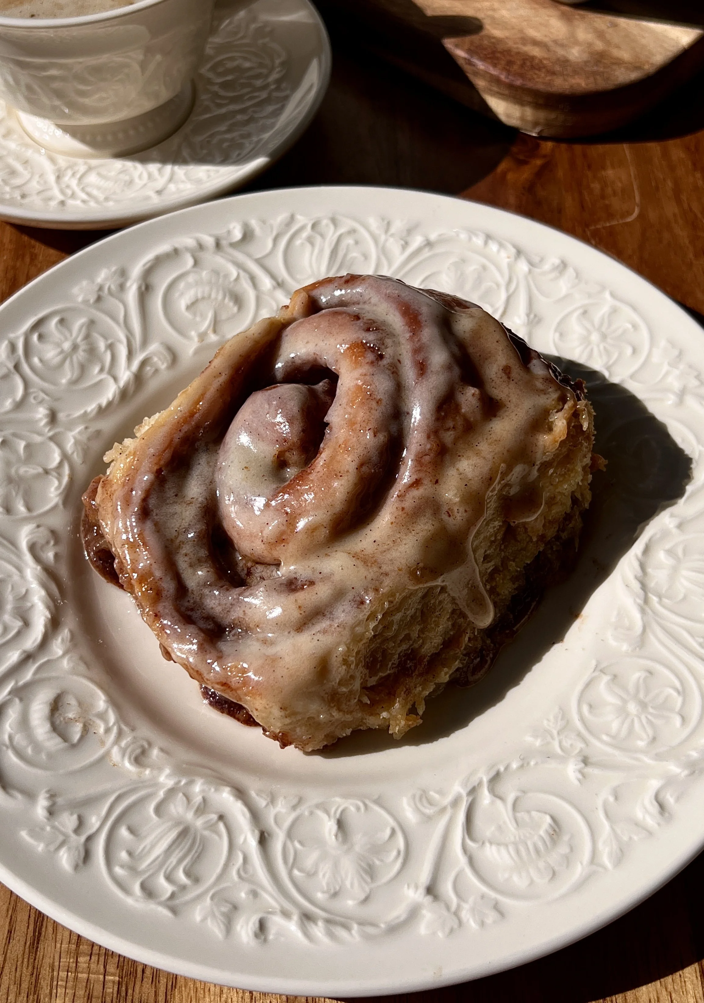 Brown butter buttermilk cinnamon rolls with brown butter cream cheese frosting served warm with a hot cup of coffee.