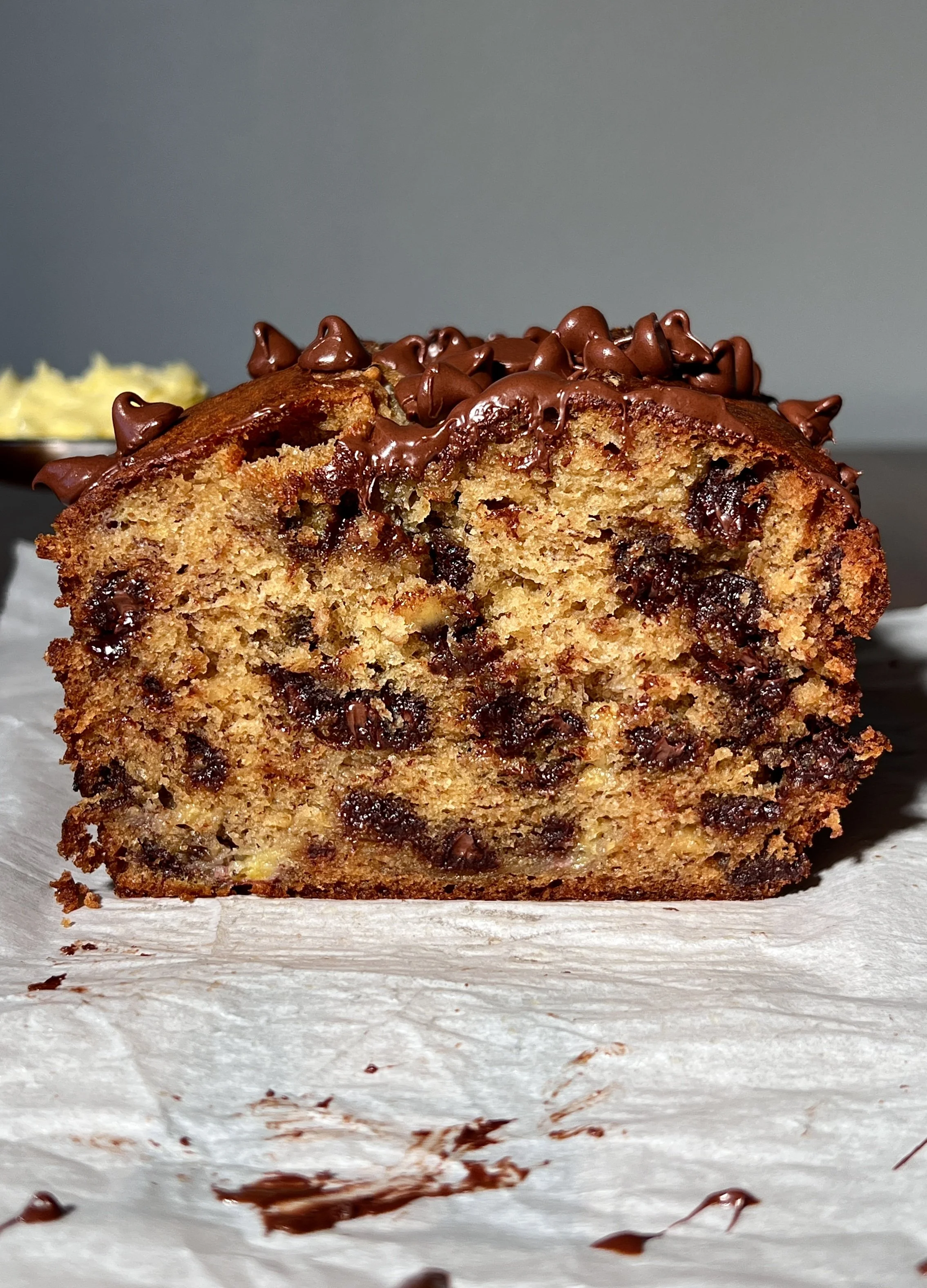 Brown butter banana bread loaf with melty chocolate chips, baked until golden, sliced and served warm with butter, flaky sea salt, and a cup of coffee.