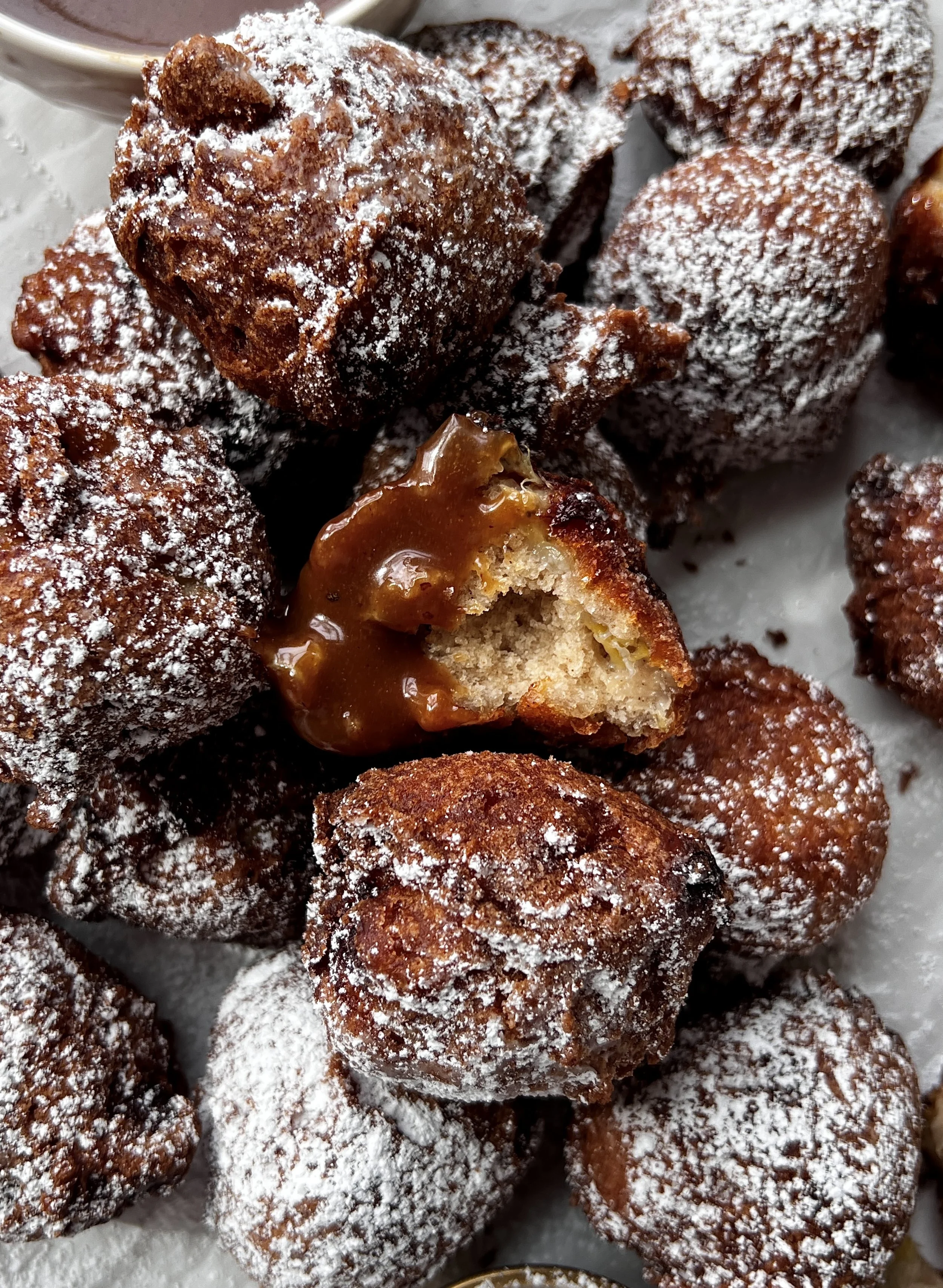 Banana fritters with soft, fluffy centers and crisp golden exteriors, served warm with powdered sugar and drizzled with silky homemade salted caramel.