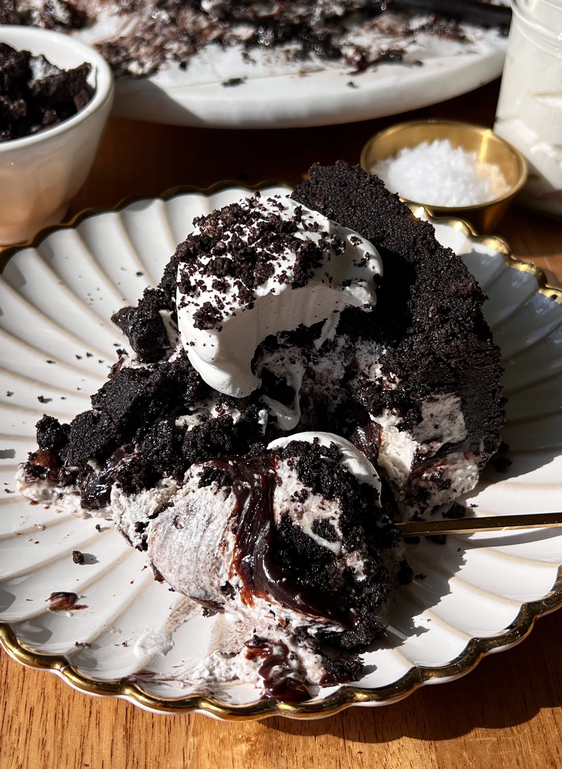 Upside down cookies and cream no-bake cheesecake with a buttery crunchy Oreo cookie crust on top inverted to serve and finished with a dollop of whipped cream and crushed Oreo cookies as the ultimate fun and impressive no-bake dessert.