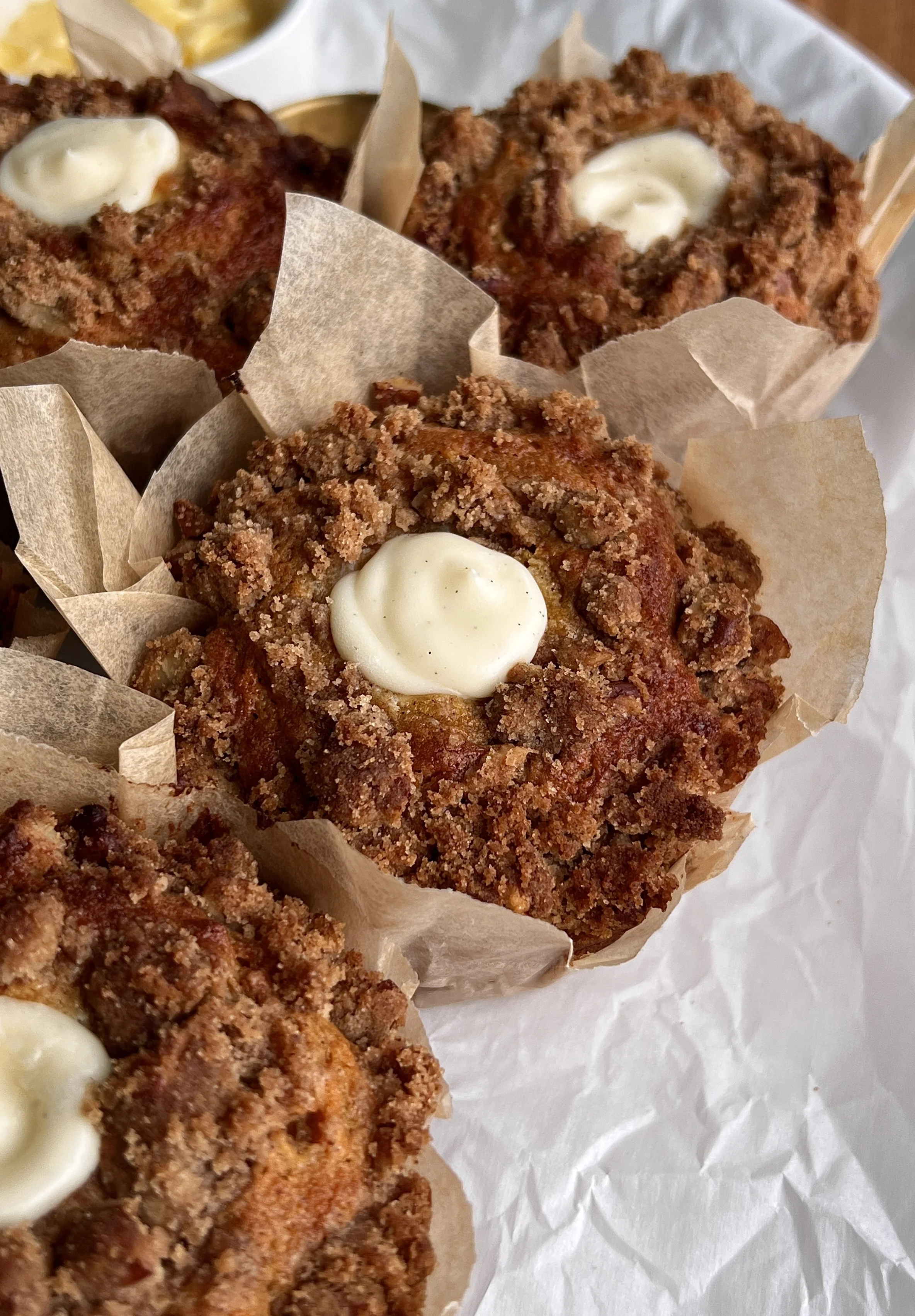 Close-up of carrot cake muffin with cream cheese filling and buttery pecan streusel topping