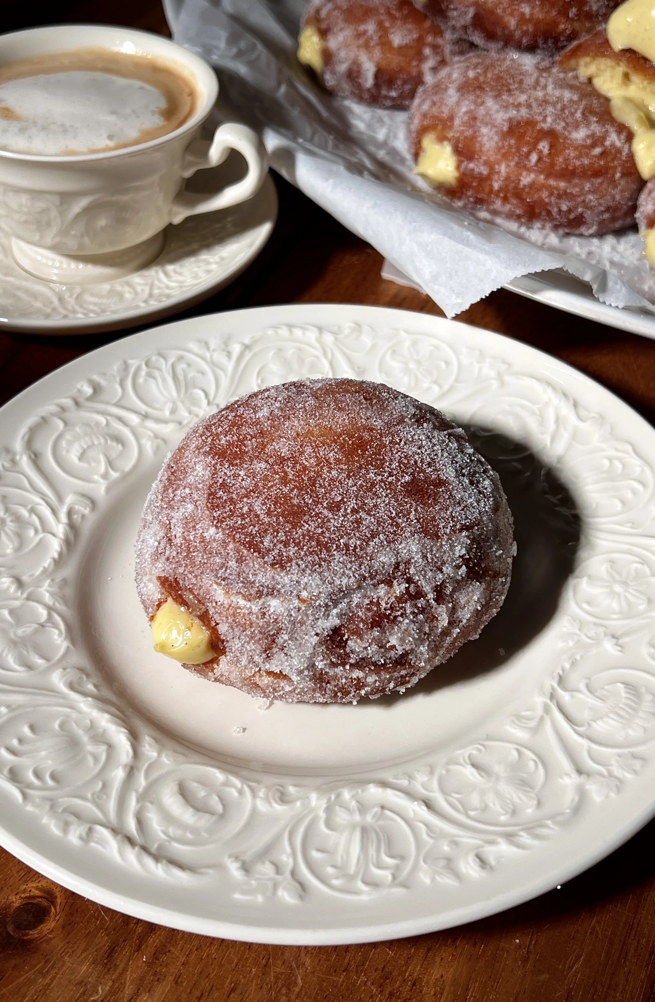 Warm vanilla bean coconut cream bomboloni rolled in sugar and served with a cup of coffee.