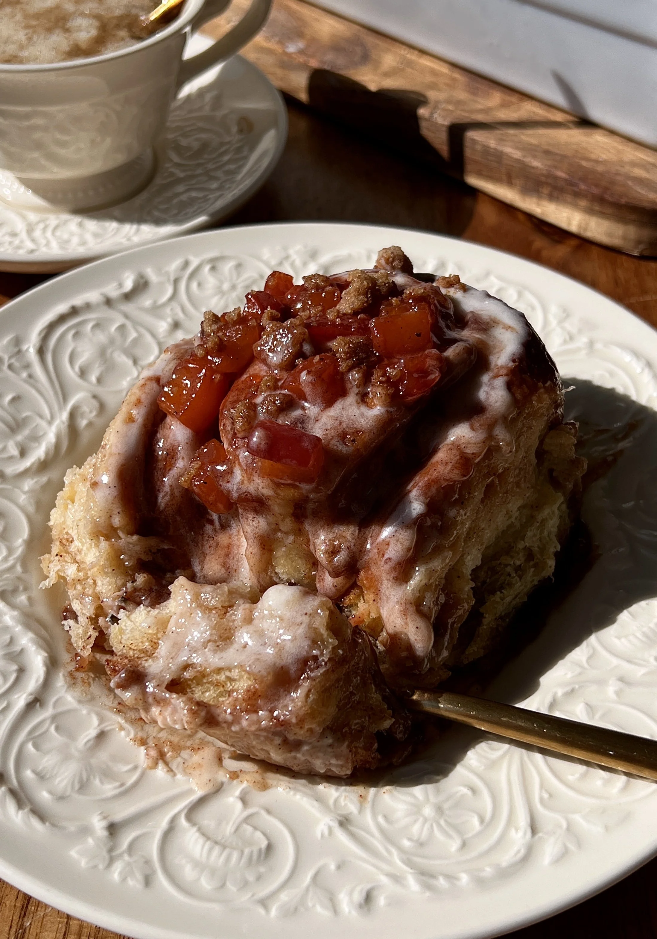 Close-up of a pillowy soft and fluffy peach cobbler cinnamon roll with a gooey brown sugar cinnamon filling and warm spiced homemade peach compote tucked inside every swirl.