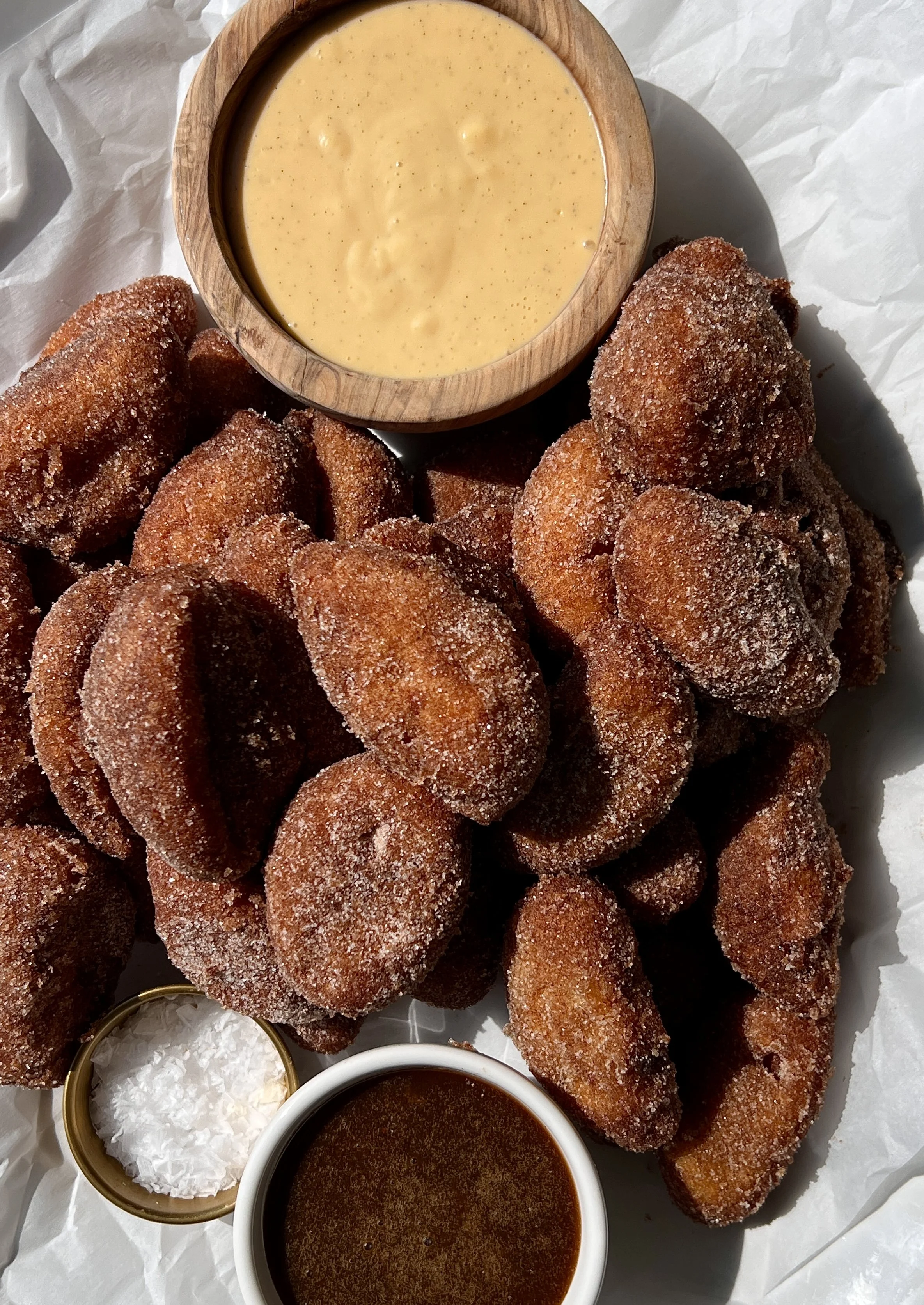 Close-up of a golden and crisp buttermilk fried peach rolled in cinnamon sugar with a warm and juicy peach inside served with crème anglaise and salted caramel.