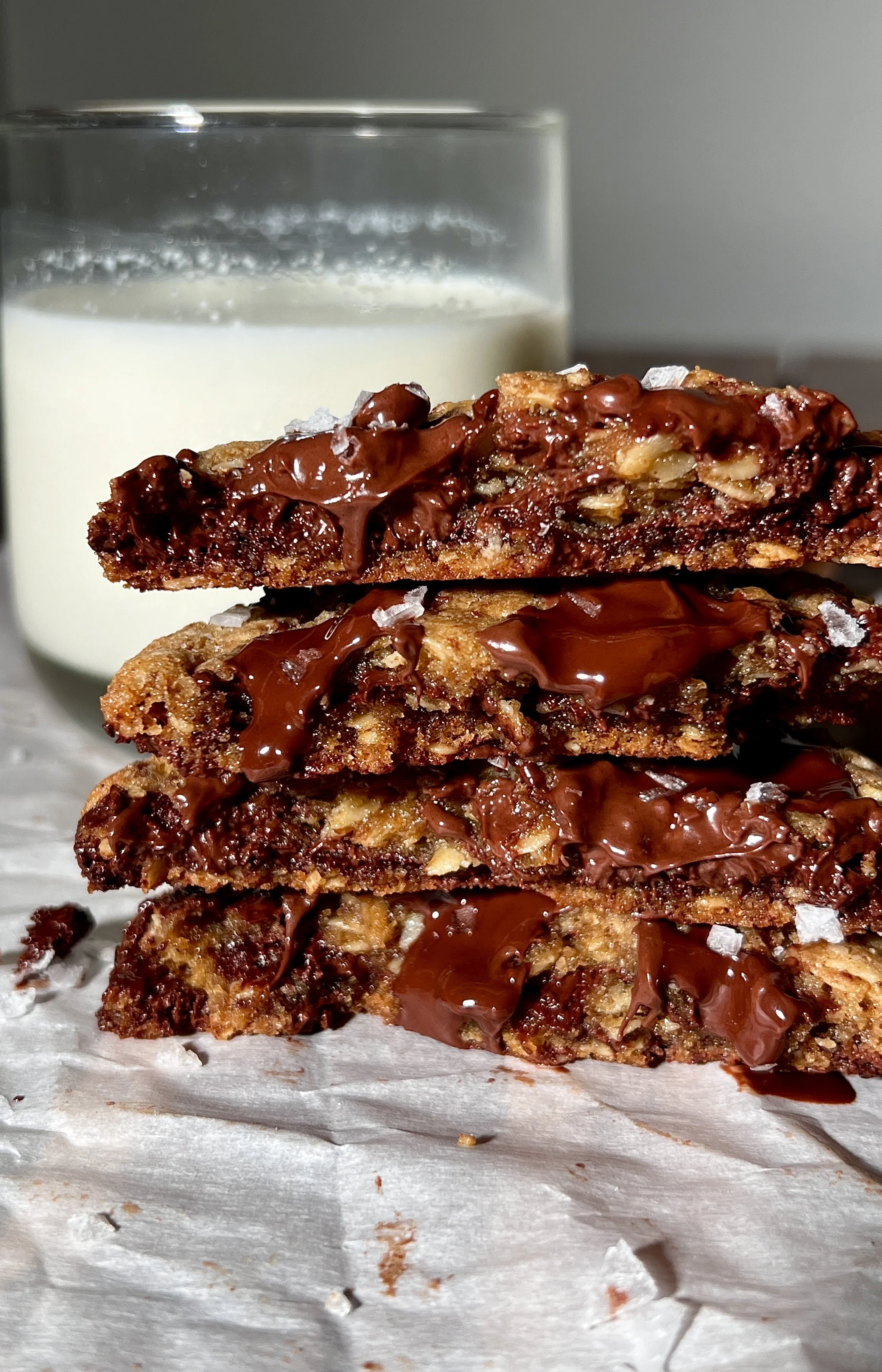 Brown butter oatmeal chocolate chip cookies with crisp golden edges and gooey centers, studded with melty chocolate chips and finished with flaky sea salt, served warm with a glass of milk.