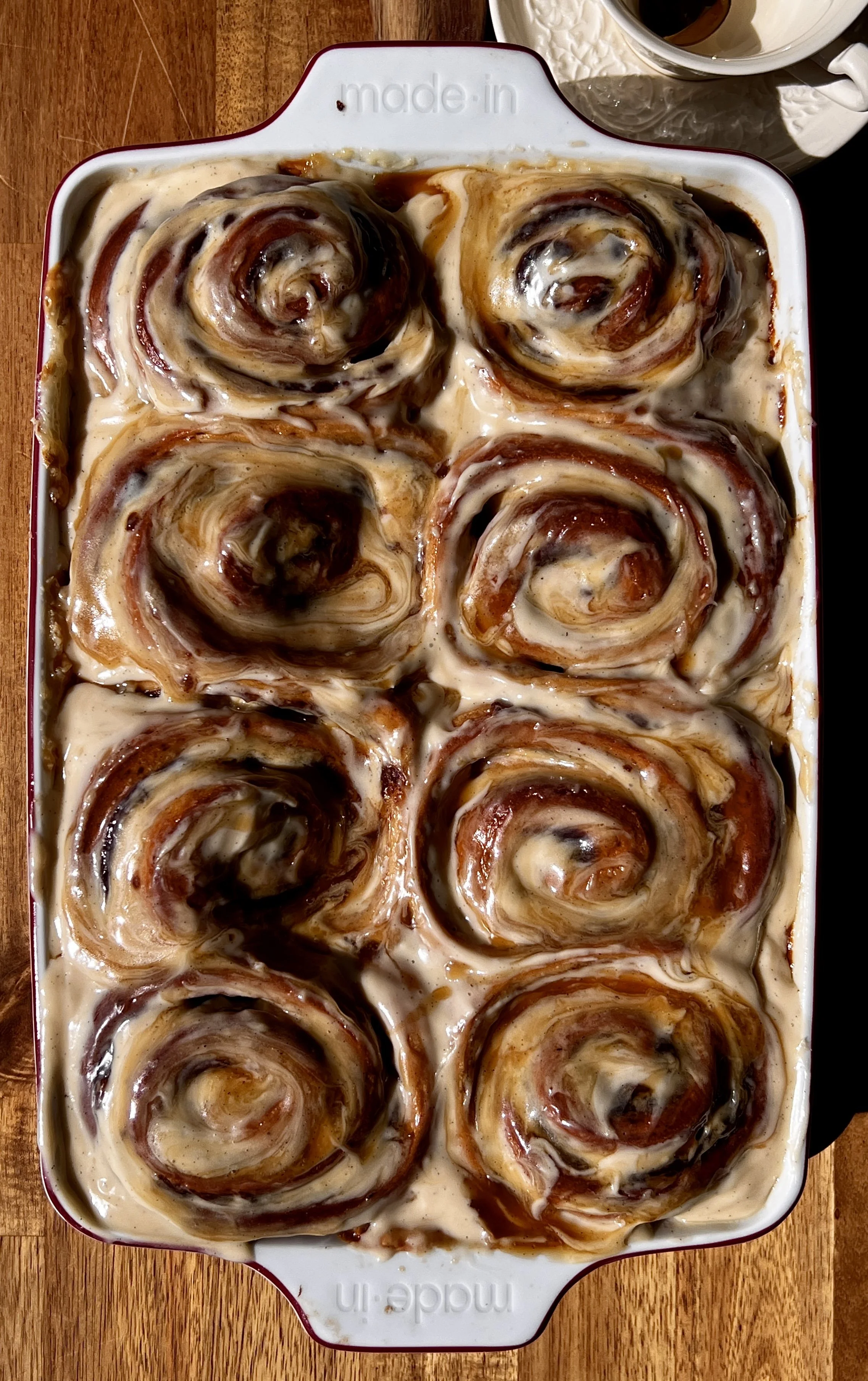 Sticky toffee pudding cinnamon rolls with a maple toffee sauce and brown sugar cream cheese frosting melting into every swirl served warm with a hot cup of coffee.