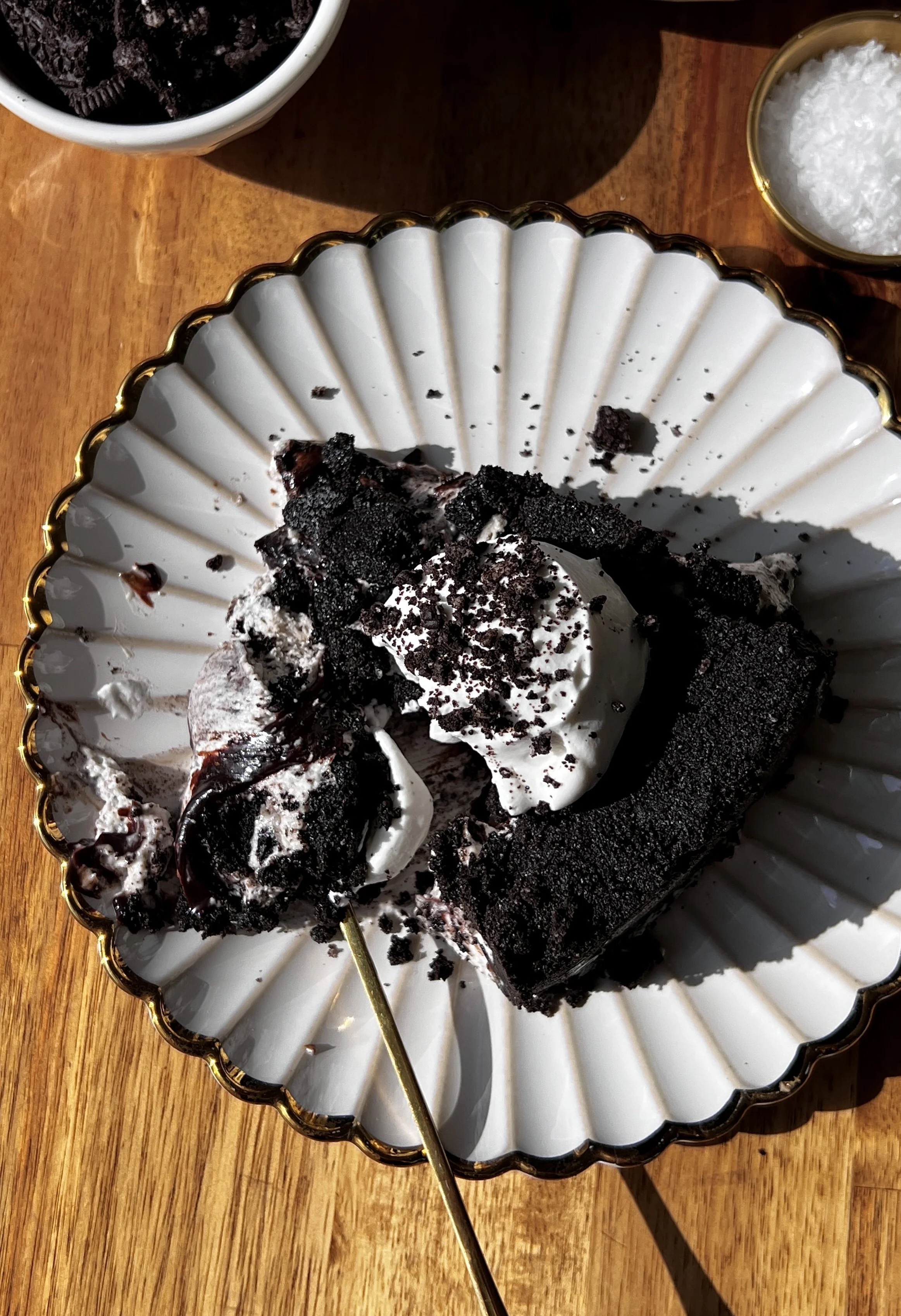 Upside down cookies and cream no-bake cheesecake with a buttery crunchy Oreo cookie crust on top inverted to serve and finished with a dollop of whipped cream and crushed Oreo cookies as the ultimate fun and impressive no-bake dessert.