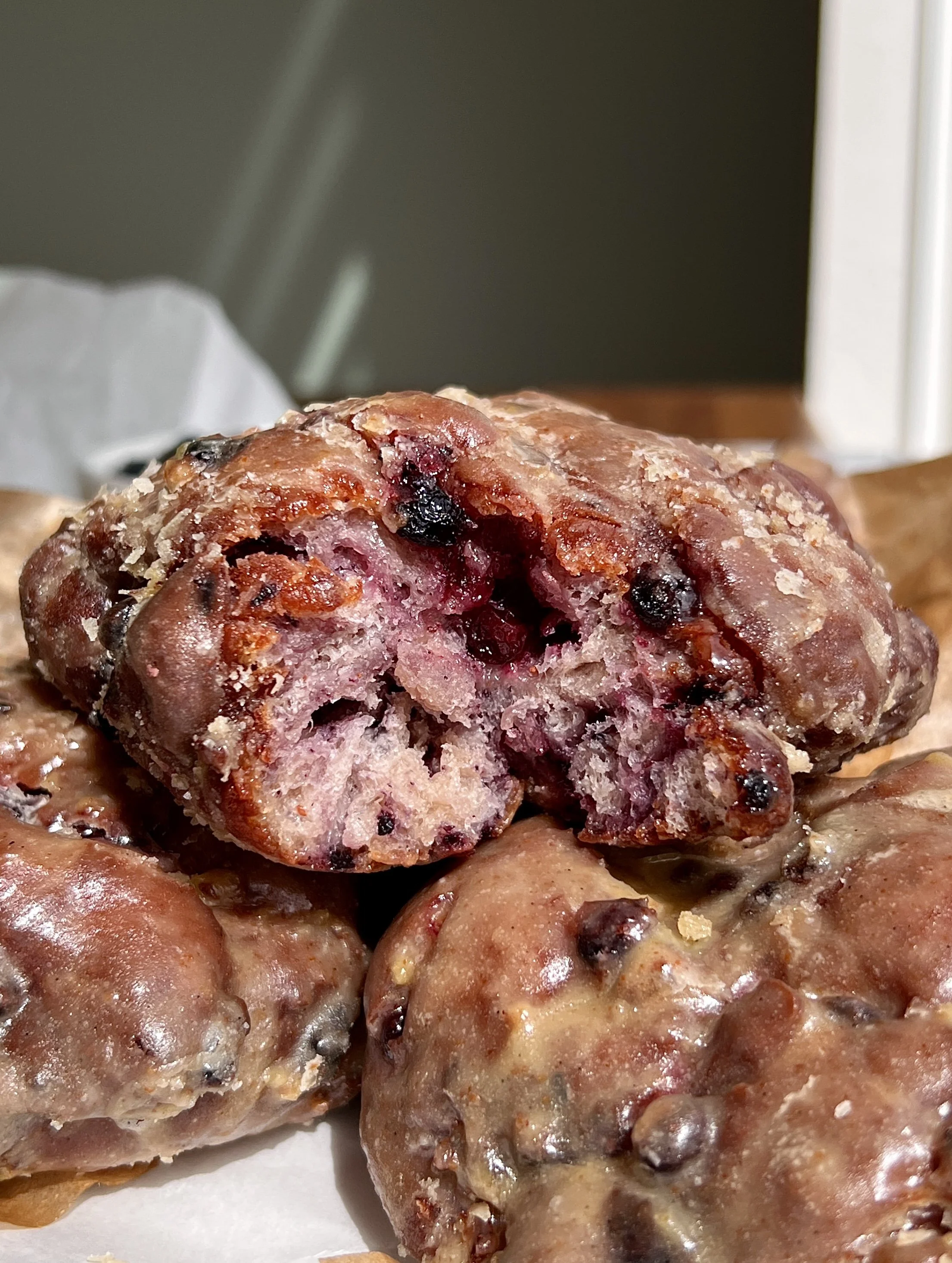 Close-up of a fluffy blueberry fritter with a golden crisp exterior and sweet wild blueberries throughout.