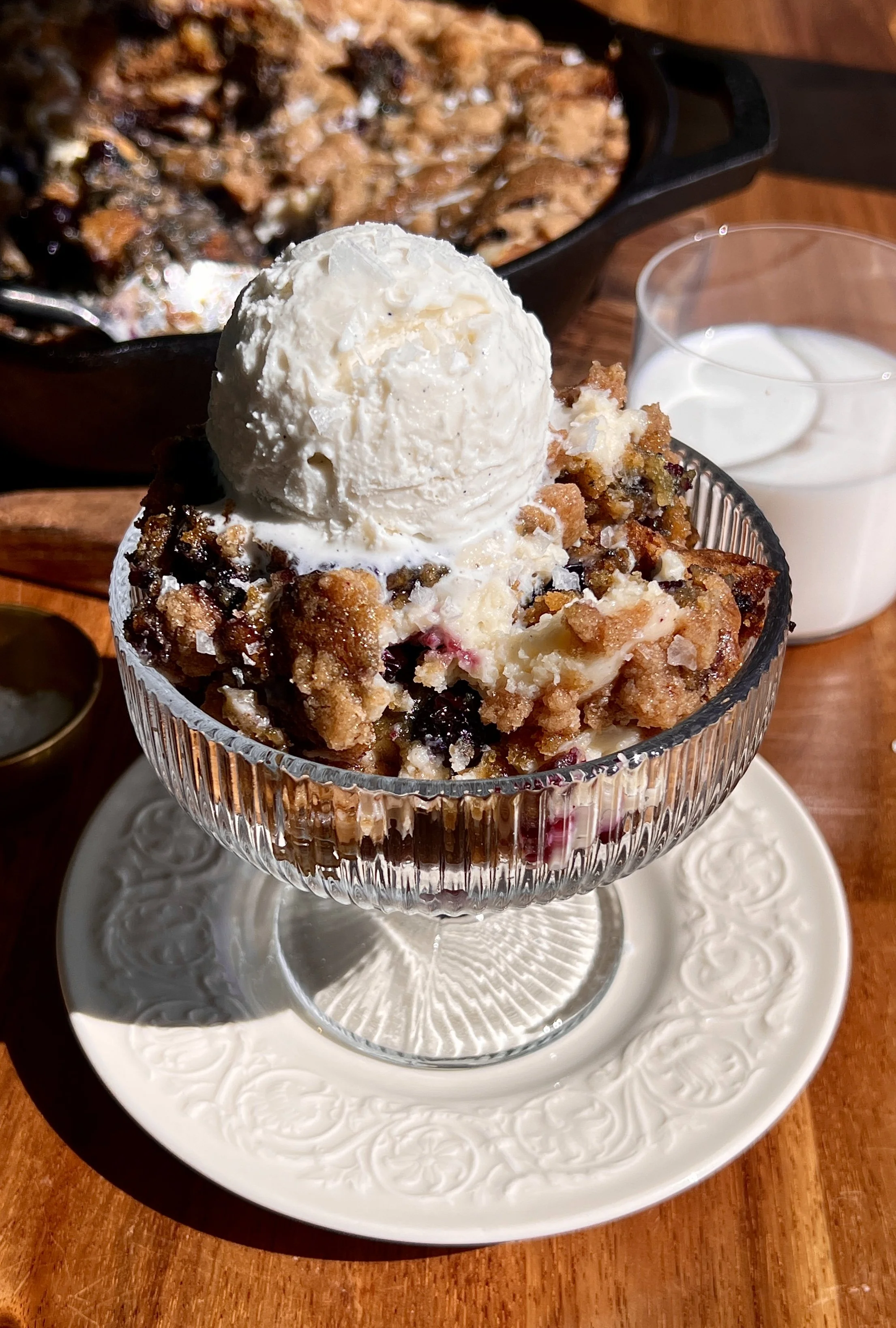 Warm brown butter blueberry crumble cookie skillet served with vanilla ice cream and flaky sea salt.