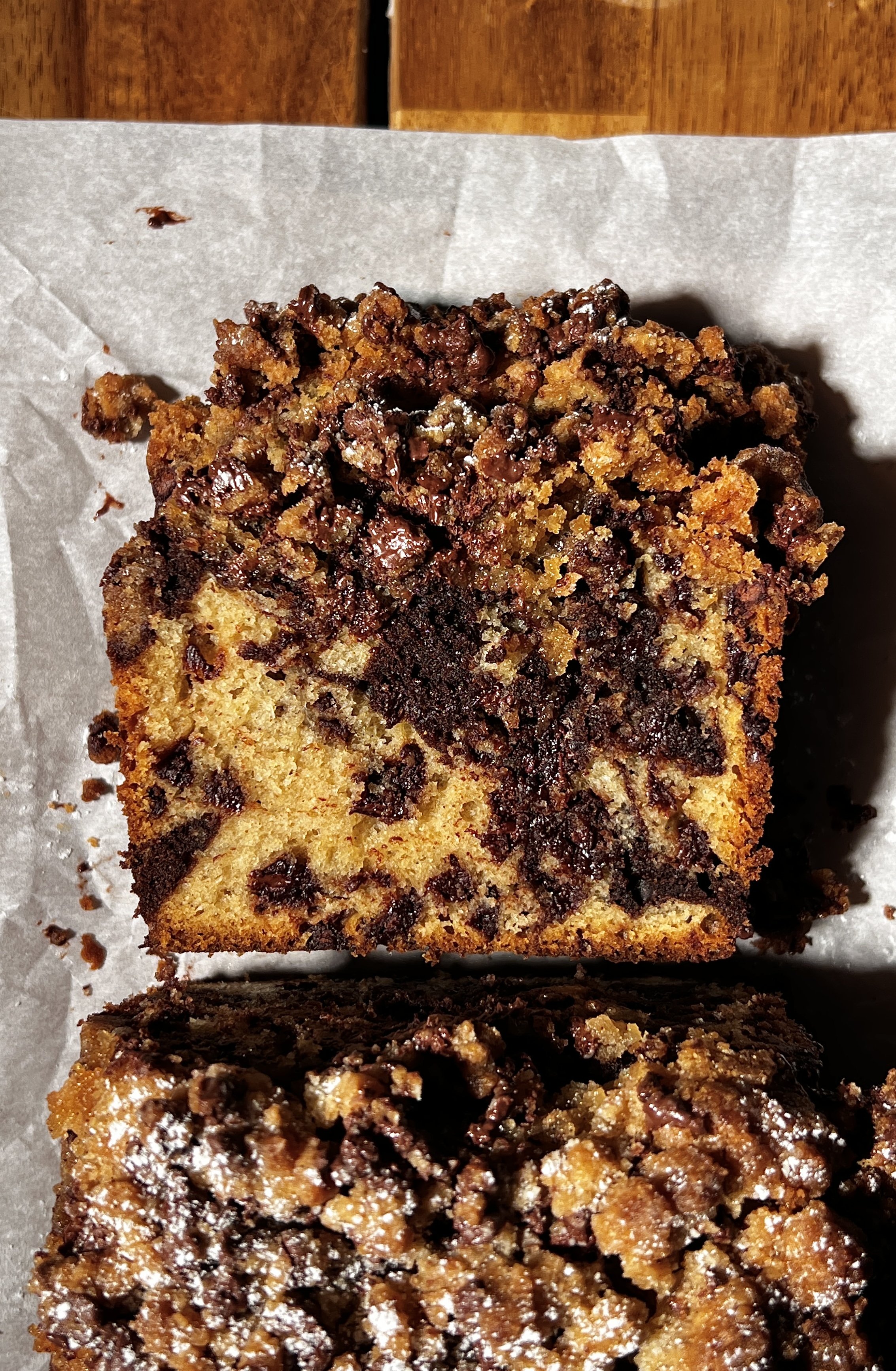 Brown butter marbled chocolate chip crumb loaf cake sliced and served warm, showing vanilla and chocolate swirled crumb, melty chocolate chips, and a buttery crumb topping, finished with flaky sea salt and coffee on the side.