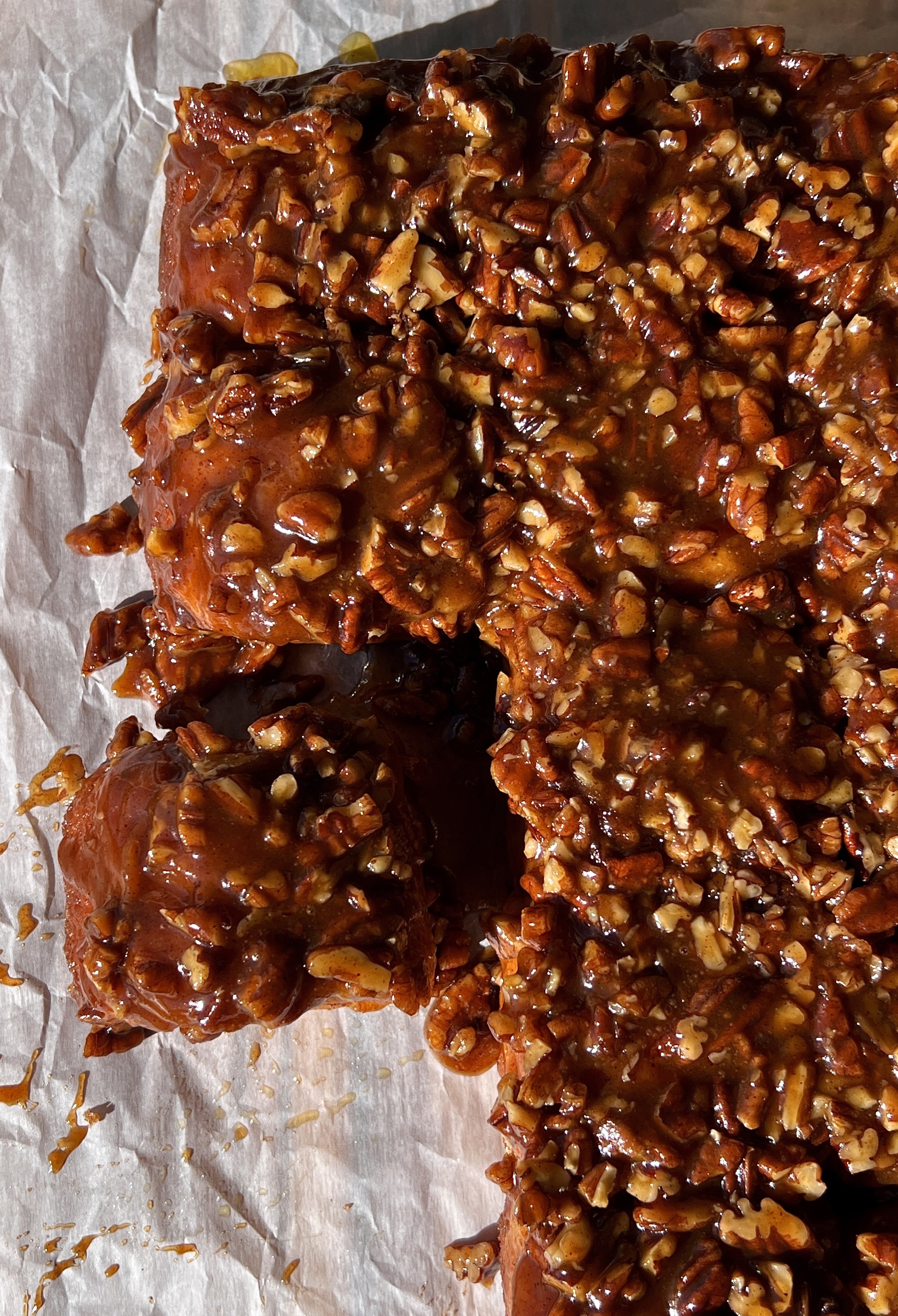 Sweet potato sticky rolls being pulled apart showing the pillowy soft fluffy and tender spiced sweet potato interior with a gooey caramelized sticky pecan topping.
