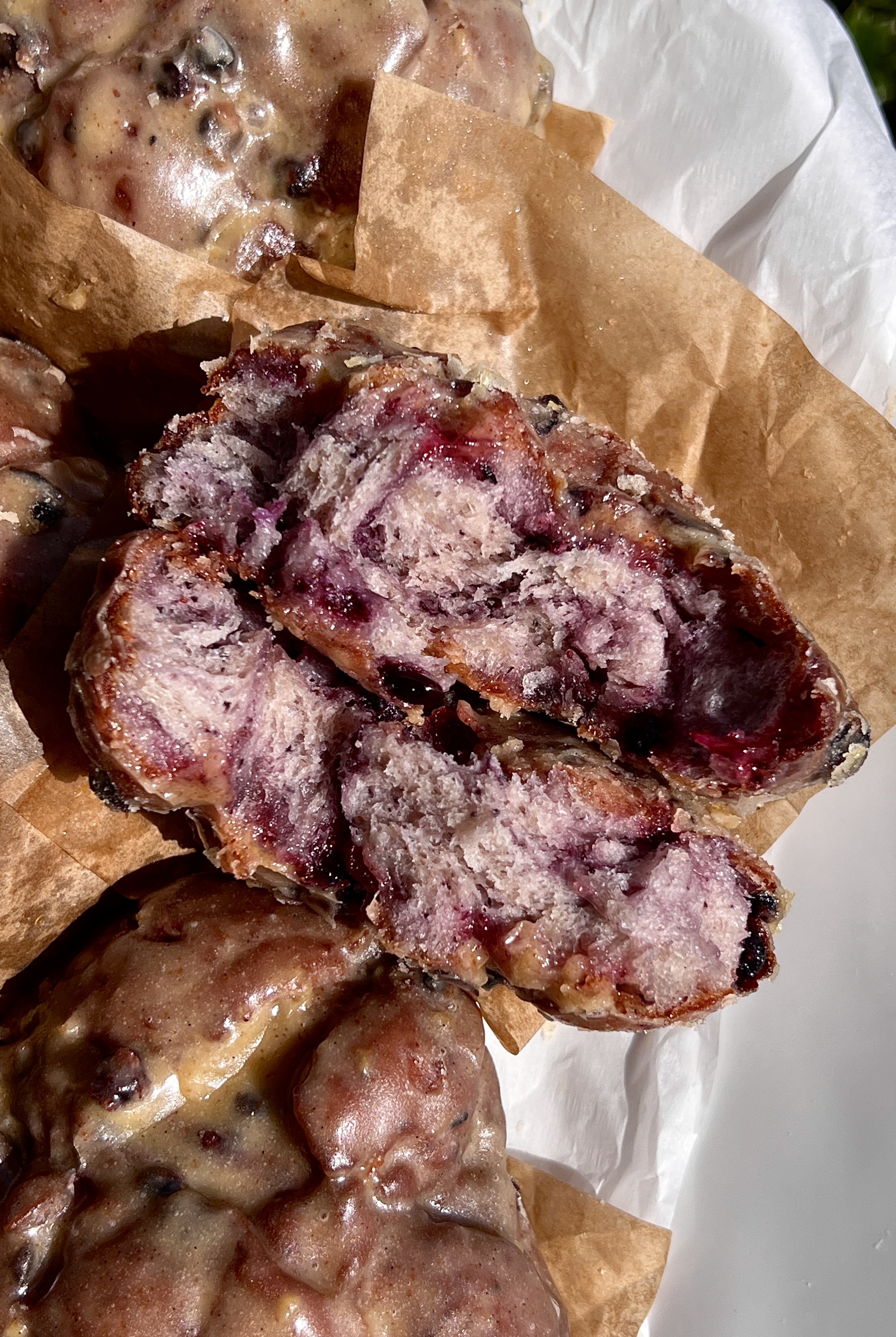 Close-up of a fluffy blueberry fritter with a golden crisp exterior and sweet wild blueberries throughout.