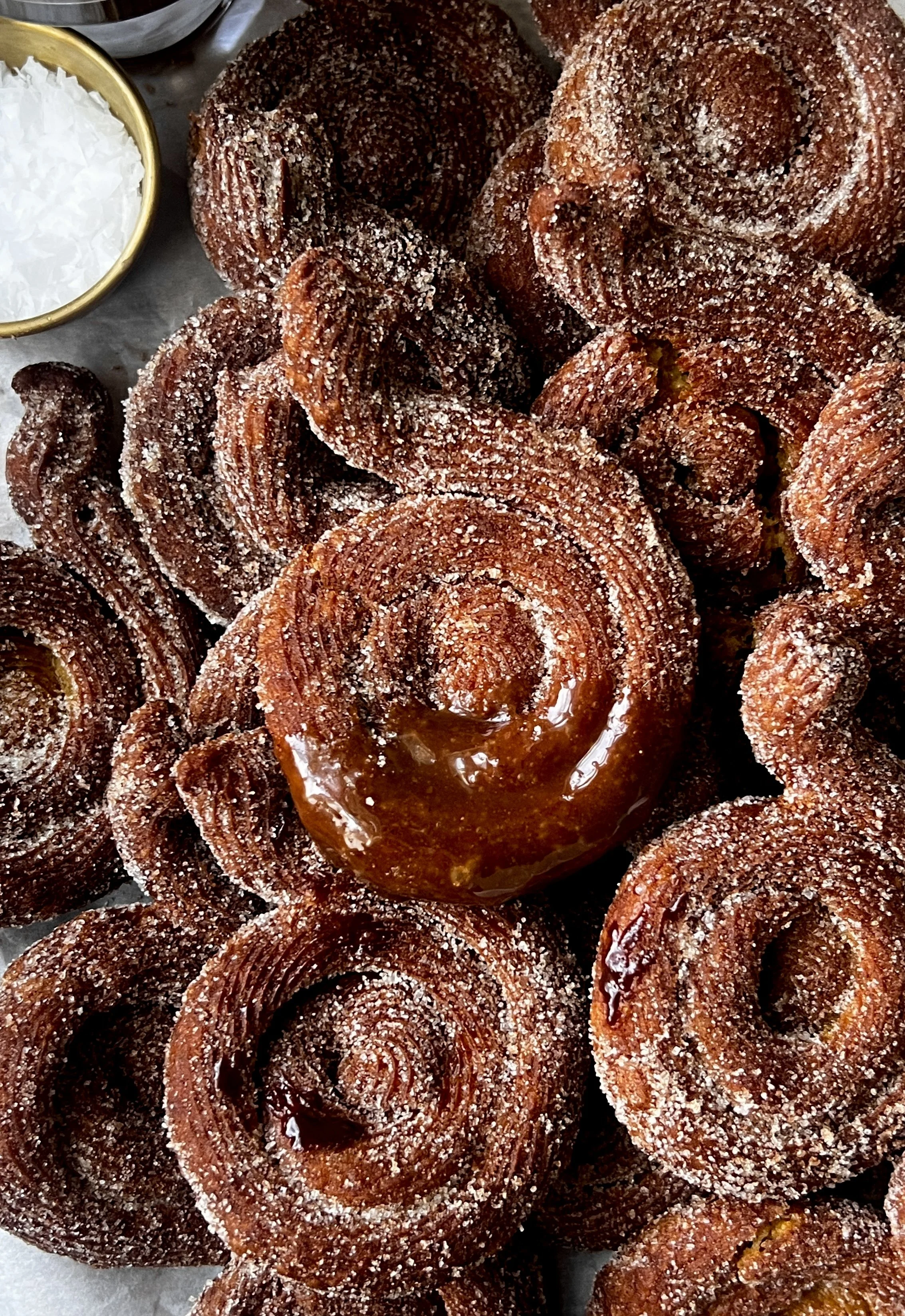 Close-up of pumpkin-shaped Brown Butter Pumpkin Churros coated in cinnamon sugar and served with salted chocolate and caramel sauce