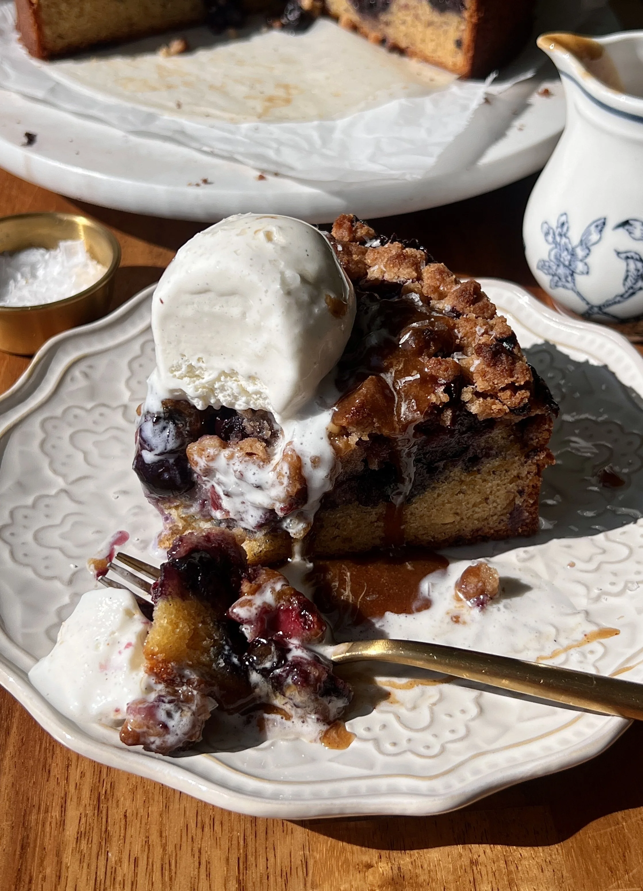 Soft and tender brown butter blueberry crumble cake with a bright jammy blueberry layer and golden buttery crumble topping served warm with a scoop of vanilla ice cream and a hot cup of coffee.