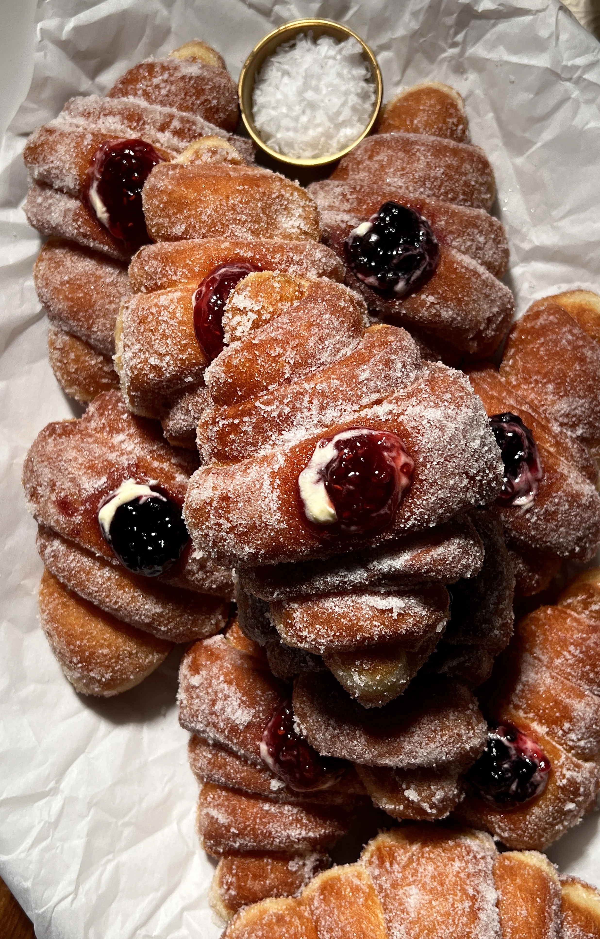 Croissant-shaped doughnuts filled with vanilla bean custard and raspberry jam, rolled in sugar and fried until golden.