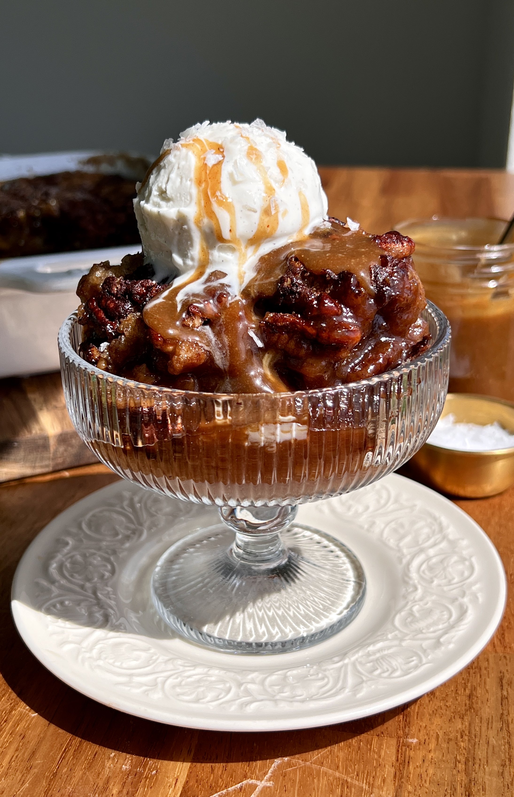 Self-saucing banana pudding cake served warm with vanilla ice cream, toasted pecans, and flaky sea salt.