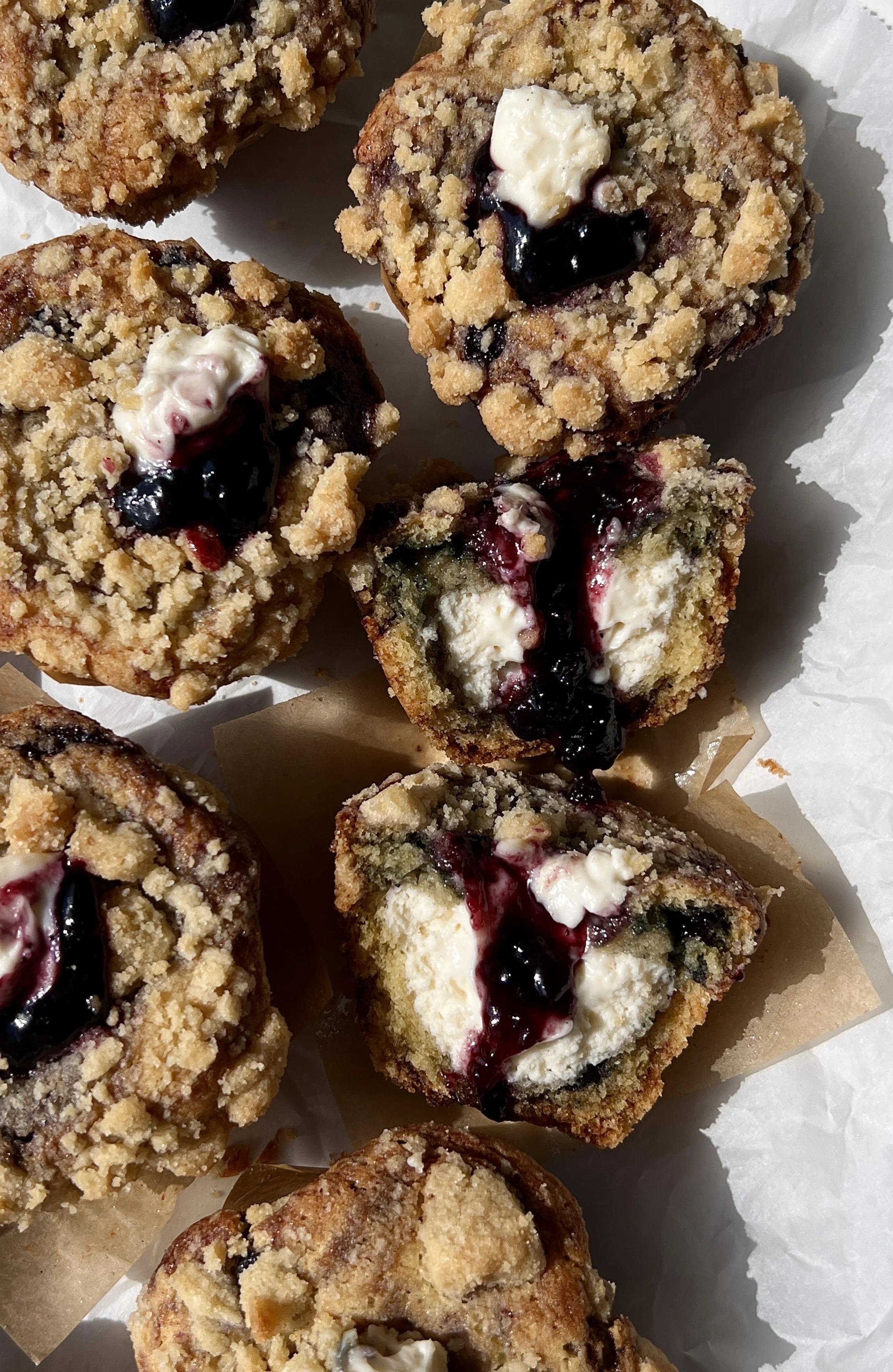 Blueberry muffin cheesecake cookie cups with a rich cheesecake filling and golden crumble topping served warm with a cold glass of milk.