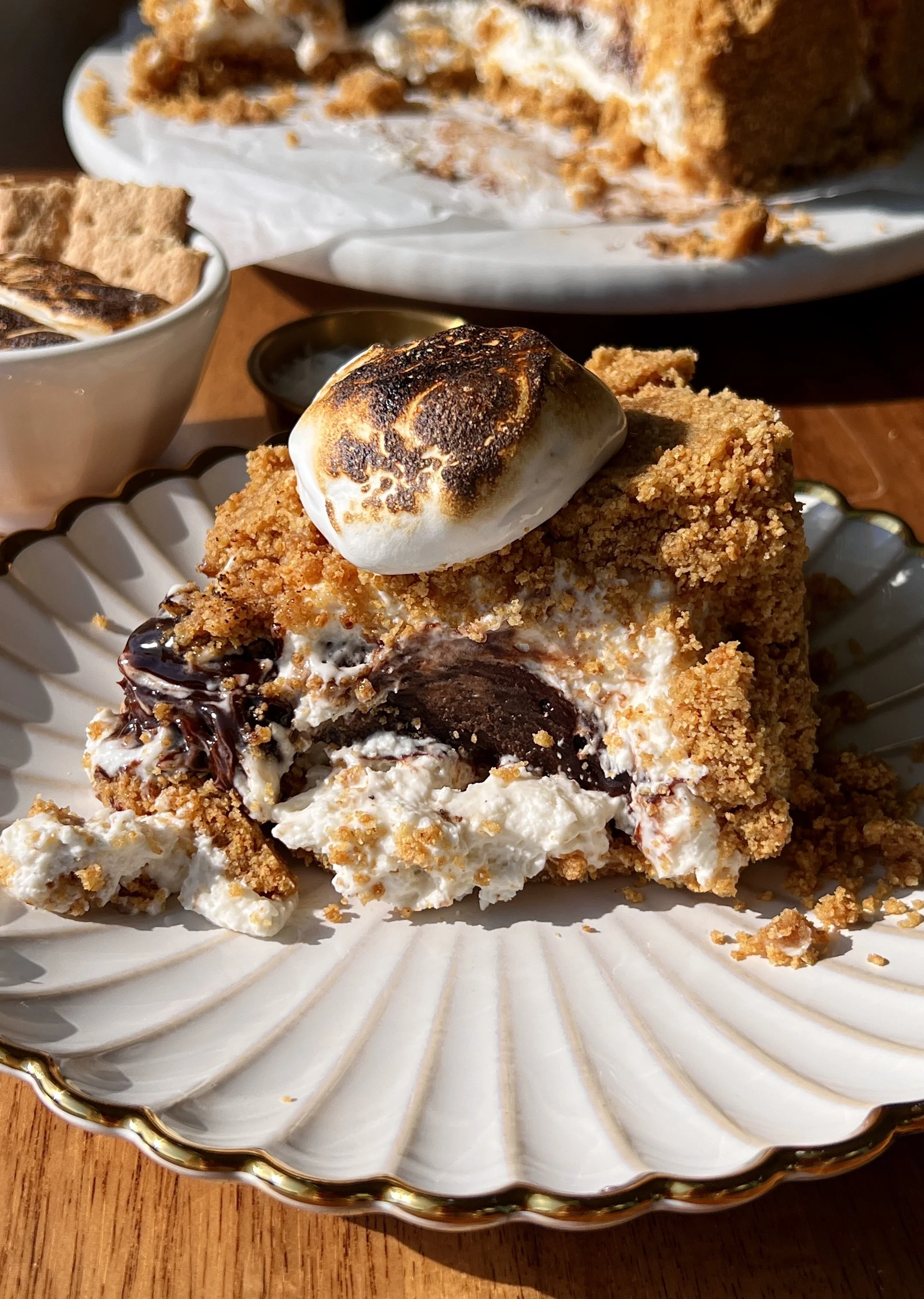 Upside down s'mores no-bake cheesecake with a perfectly crunchy graham cracker crust inverted to serve and finished with a dollop of toasted marshmallow fluff on top.