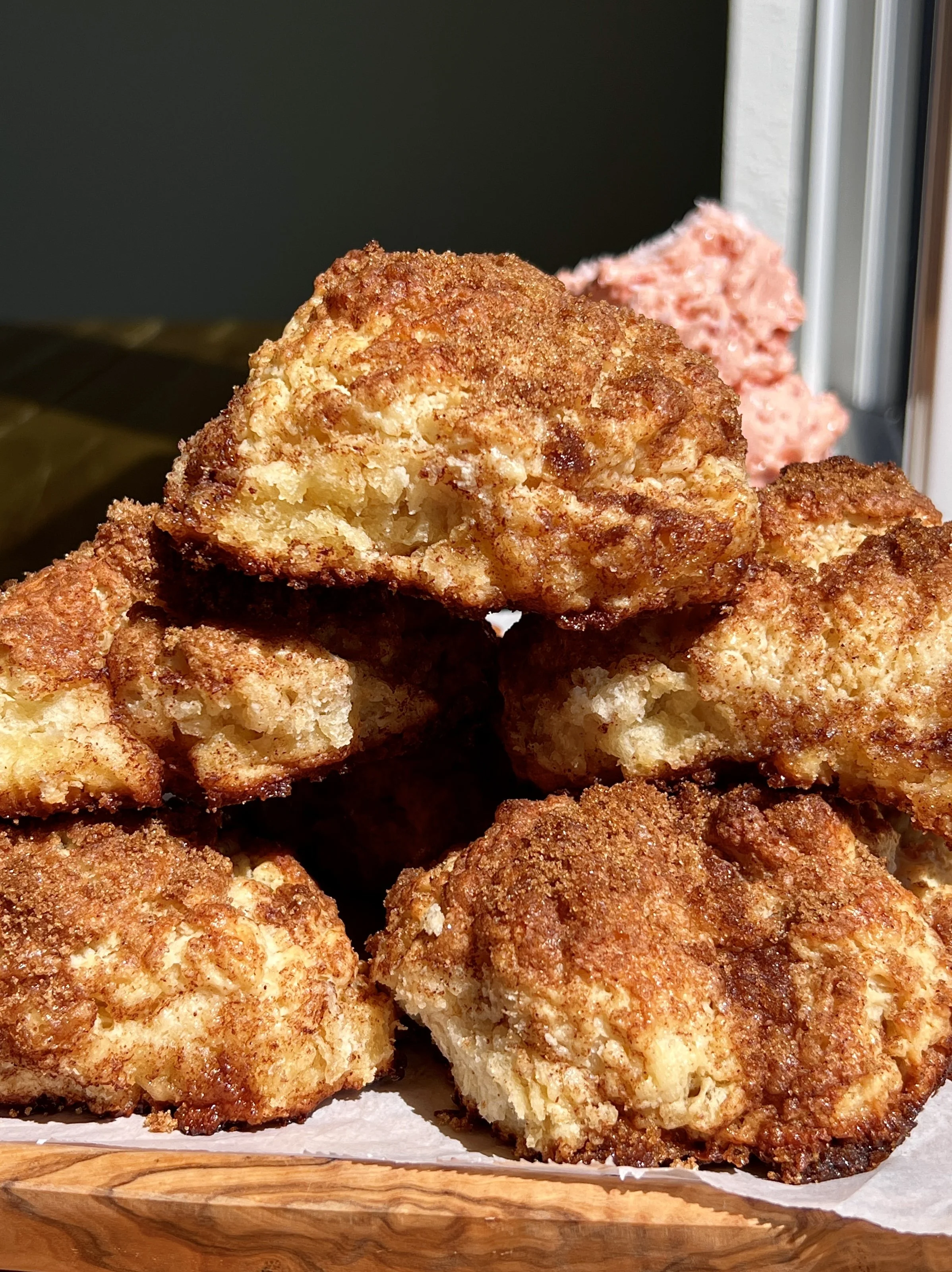 Stack of golden cinnamon crunch sourdough cathead biscuits served warm with whipped strawberry honey butter and a hot cup of coffee.