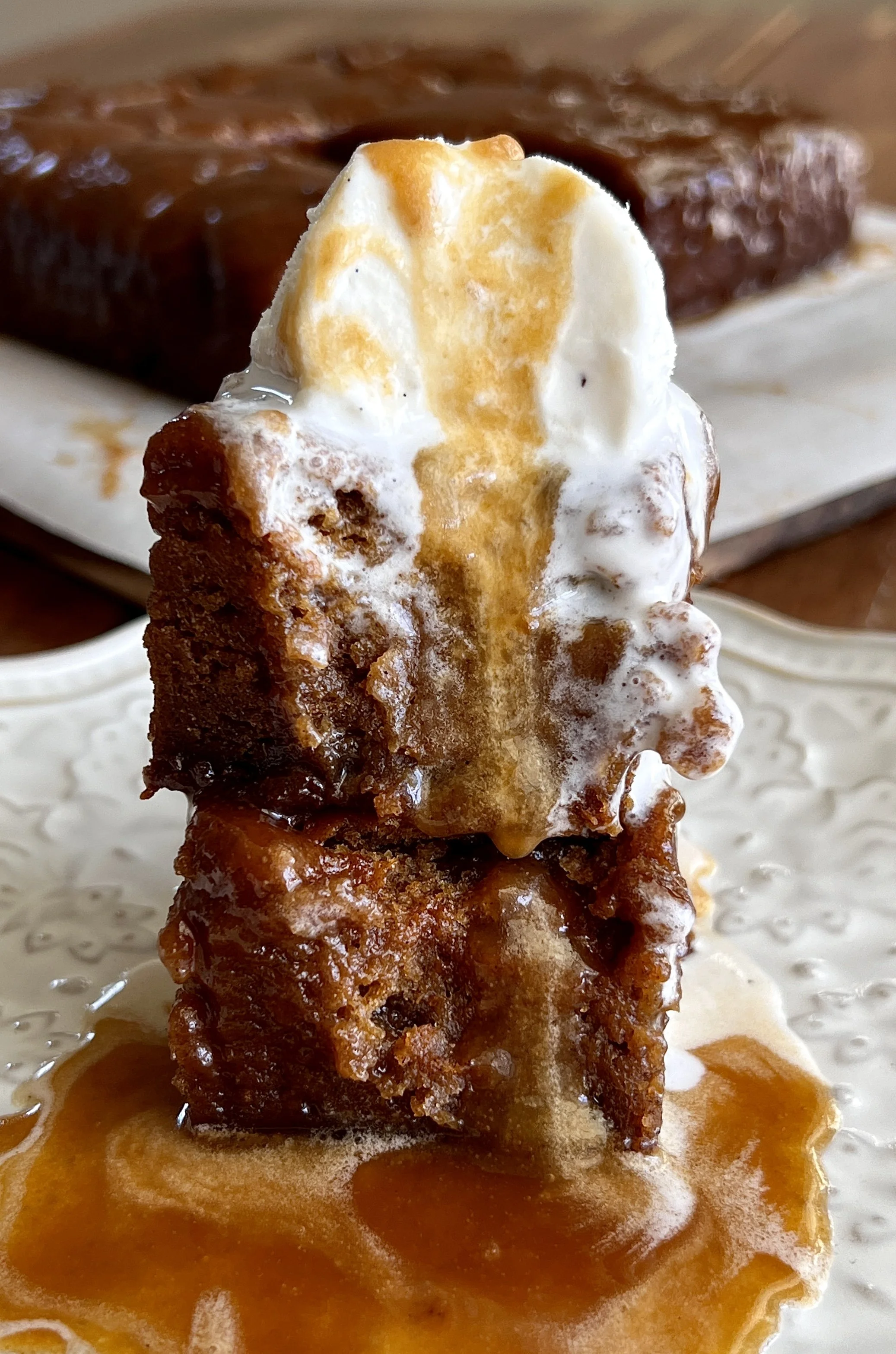 Sweet potato sticky toffee pudding served warm with a scoop of vanilla ice cream and drizzled with sweet potato sticky toffee sauce."