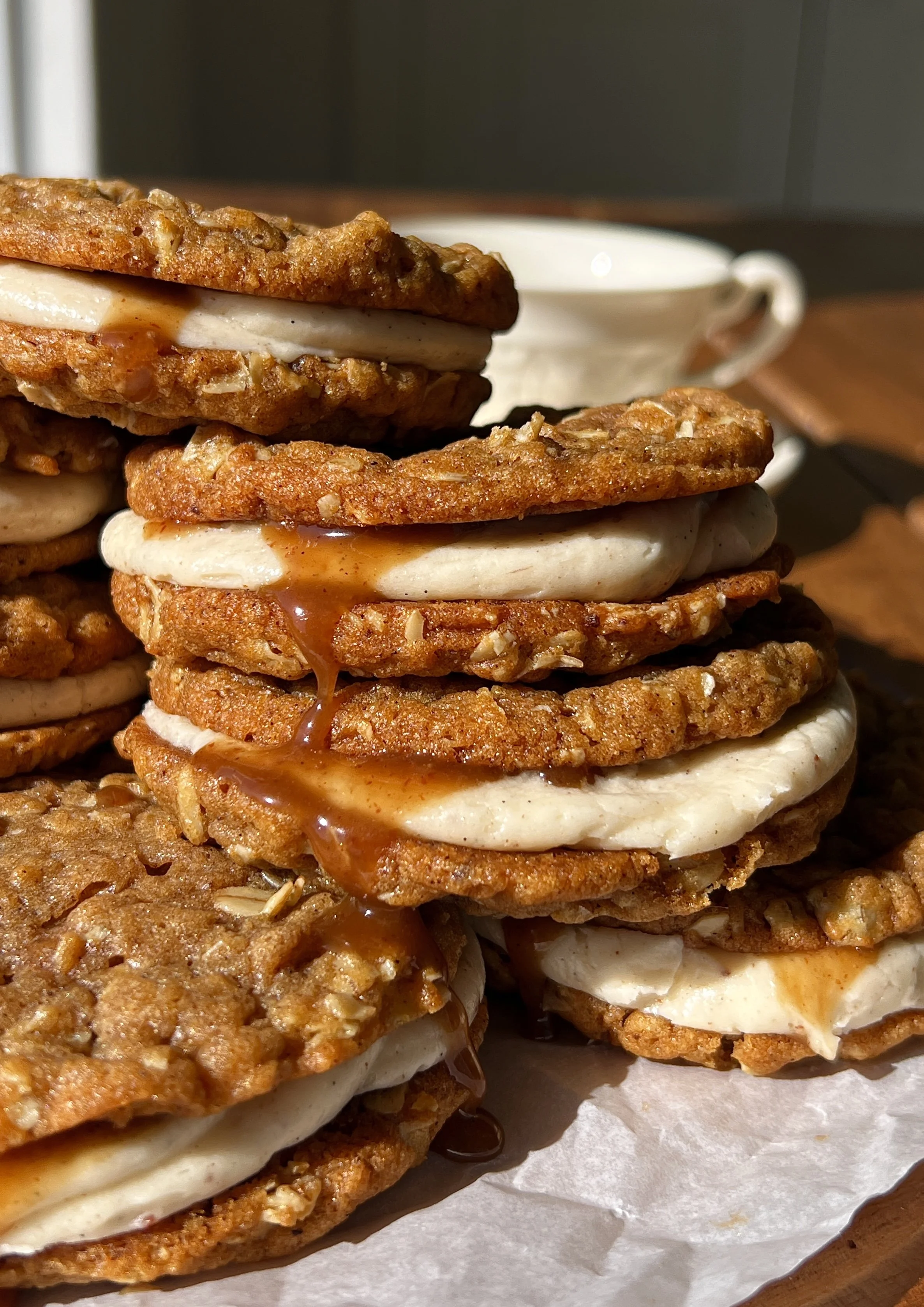 Close-up of a brown butter sweet potato oatmeal cream pie showing the soft and chewy spiced sweet potato oatmeal cookie with lush brown butter cream cheese filling and salted maple caramel in the middle.