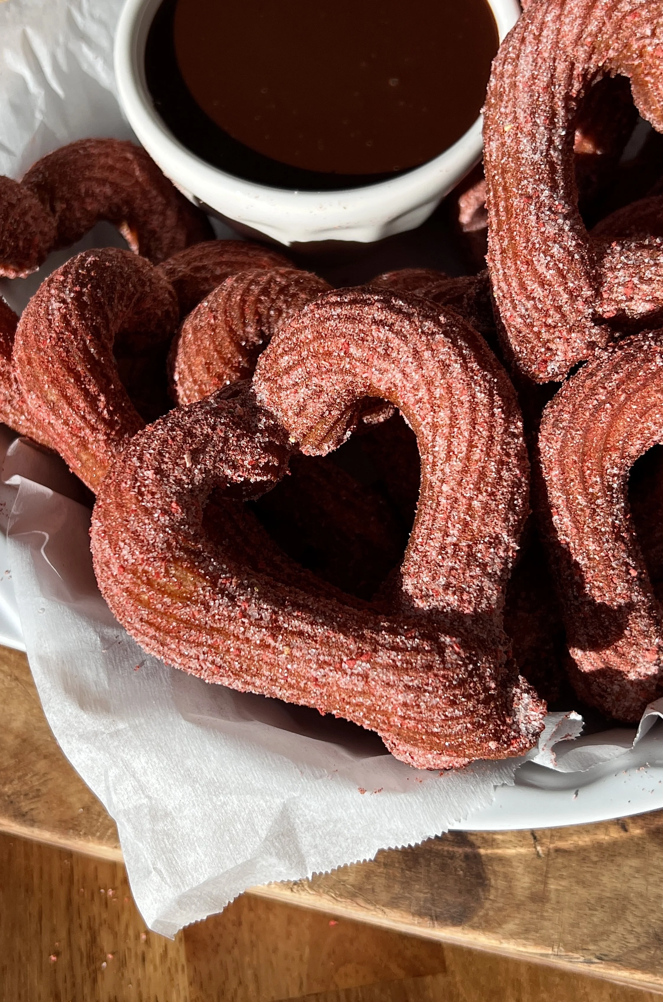 Close-up of heart-shaped churros showing the crisp exterior and soft interior with pink sugar coating.