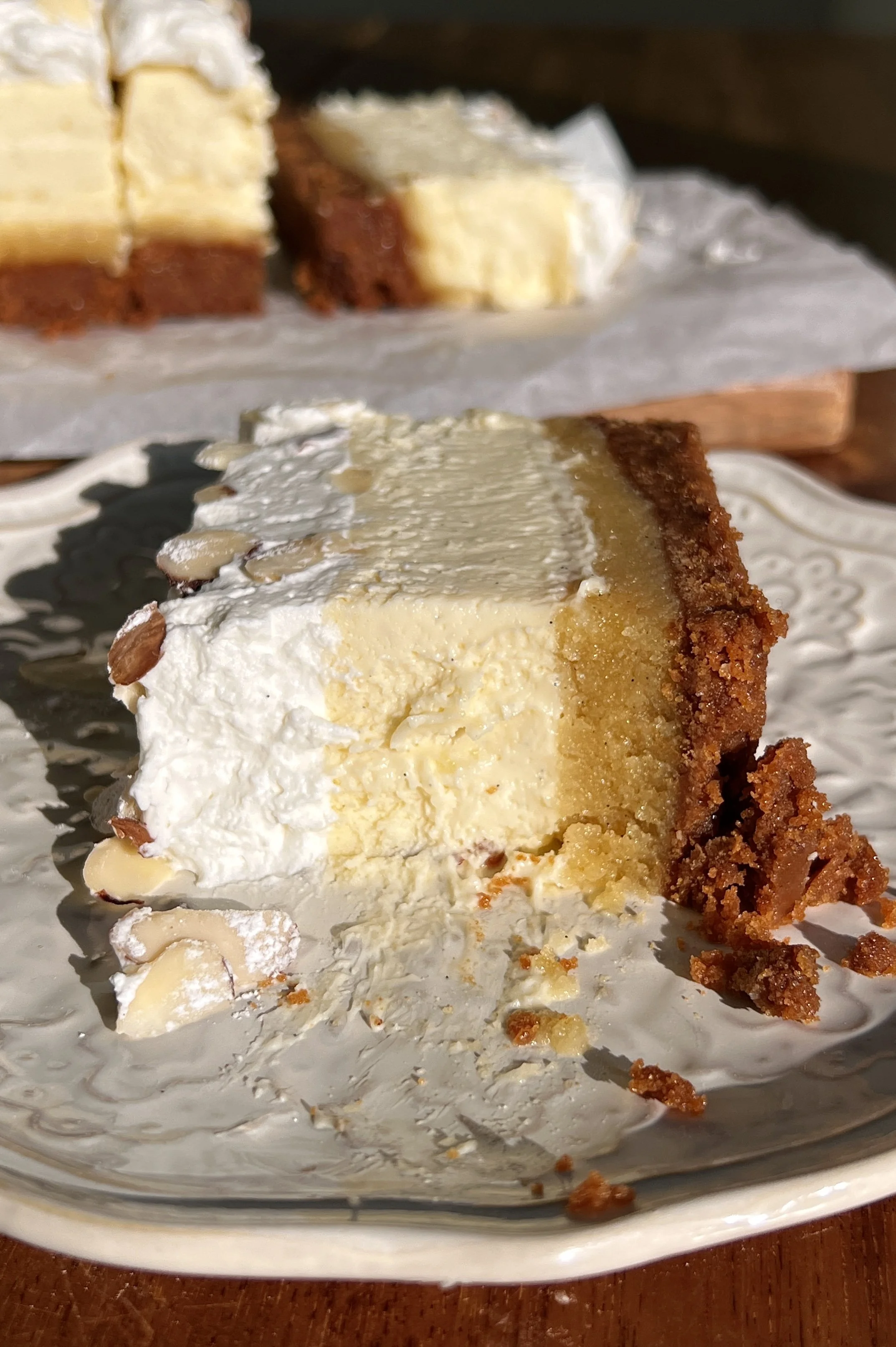 Creamy almond frangipane cheesecake bars showing layers of Biscoff crust, frangipane filling, and vanilla bean cheesecake.
