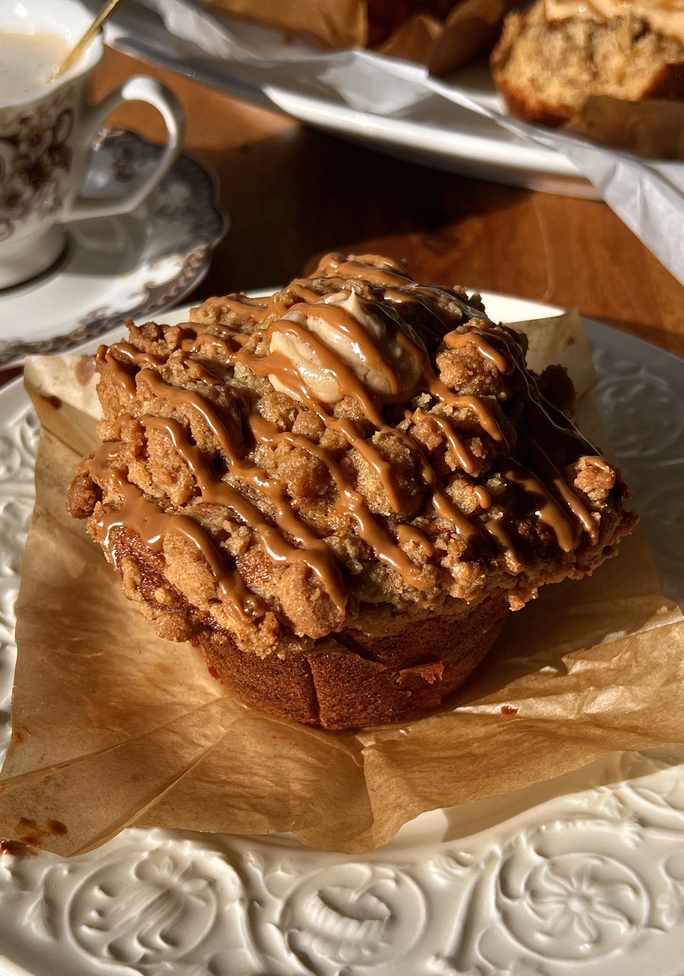 Bakery-style banana Biscoff muffins with a golden Biscoff streusel topping and rich Biscoff cream cheese filling served warm with a hot cup of coffee.