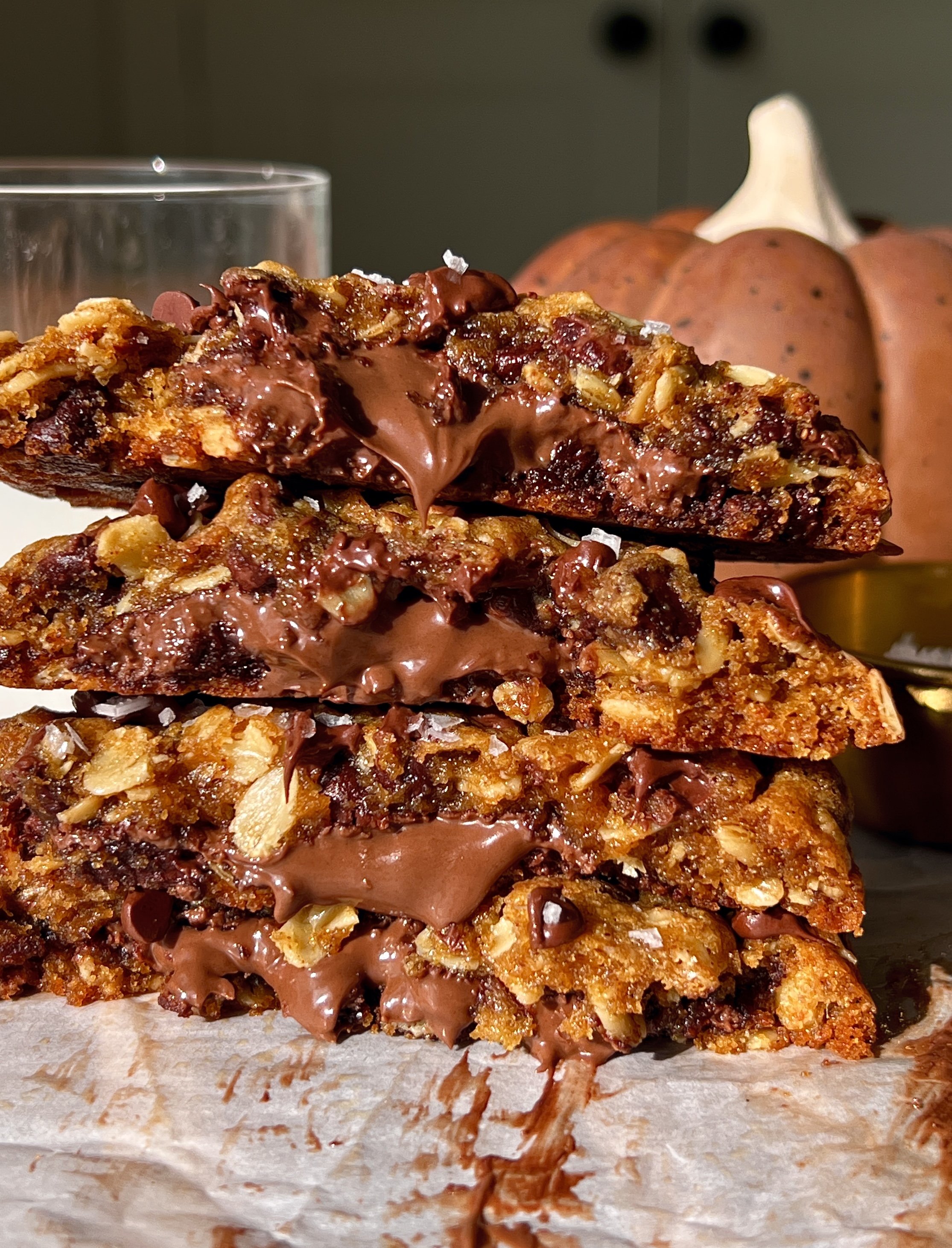 Close-up of a Nutella stuffed pumpkin oatmeal cookie with brown butter showing the soft and gooey center with melty chocolate chips perfectly crisp golden edges and a sprinkle of flaky sea salt.