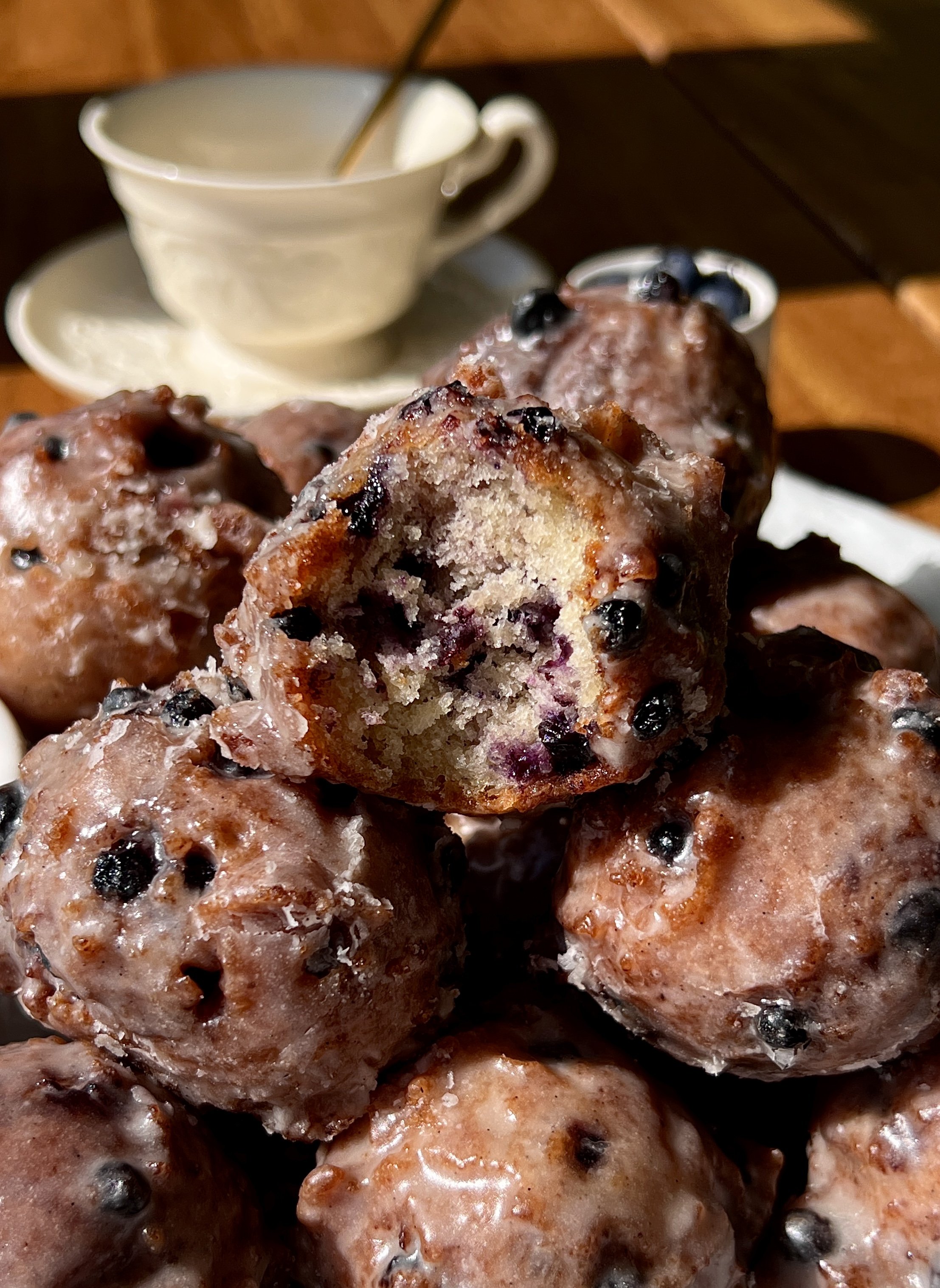 Sourdough blueberry fritter bites coated in a silky vanilla bean glaze served warm with a hot cup of coffee.