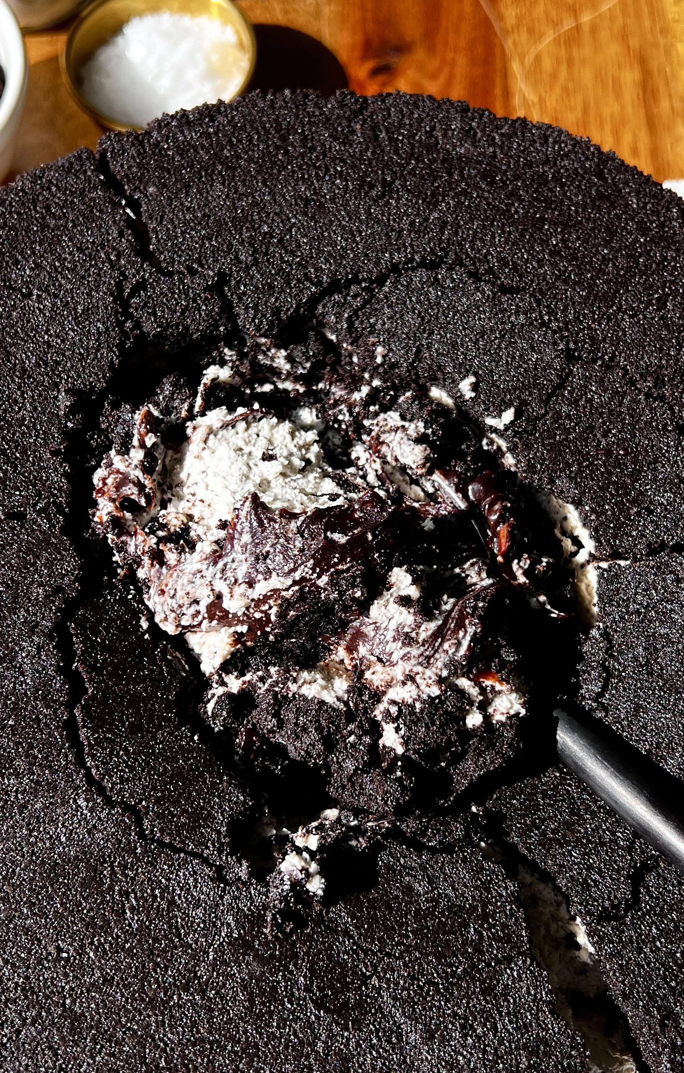 Close-up of an upside down cookies and cream no-bake cheesecake showing the rich and creamy cookies and cream cheesecake filling and rich decadent hot fudge sauce layer throughout.