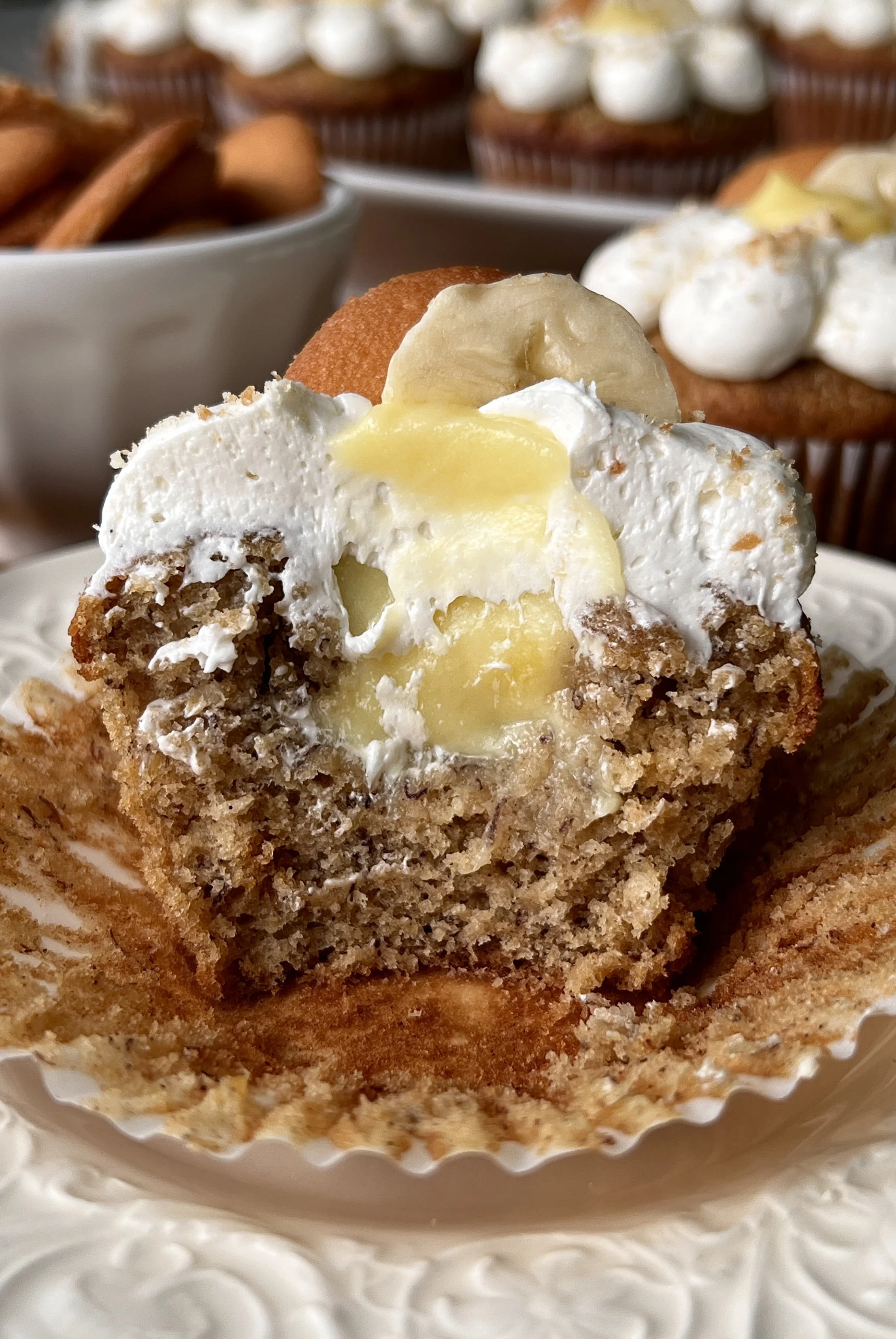 Close-up of a brown butter banana pudding cupcake filled with classic vanilla pudding and topped with light and fluffy whipped buttercream and crushed Nilla wafers.