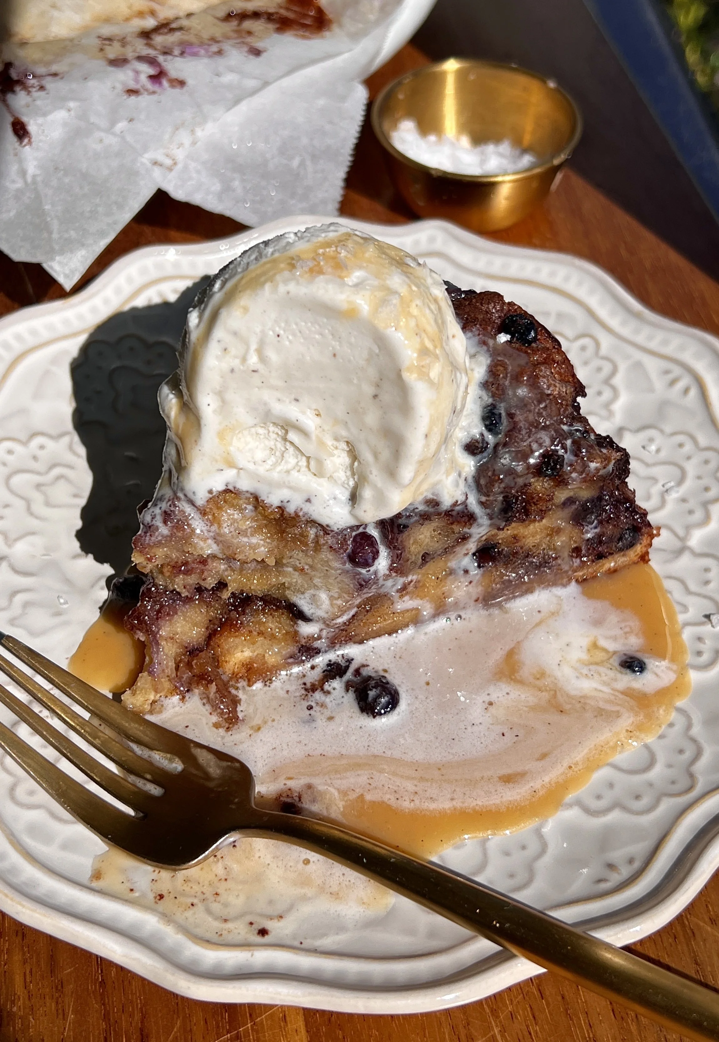Soft and golden blueberry cinnamon roll bread pudding made with brioche bread and vanilla bean custard served warm with a scoop of vanilla ice cream and flaky sea salt.