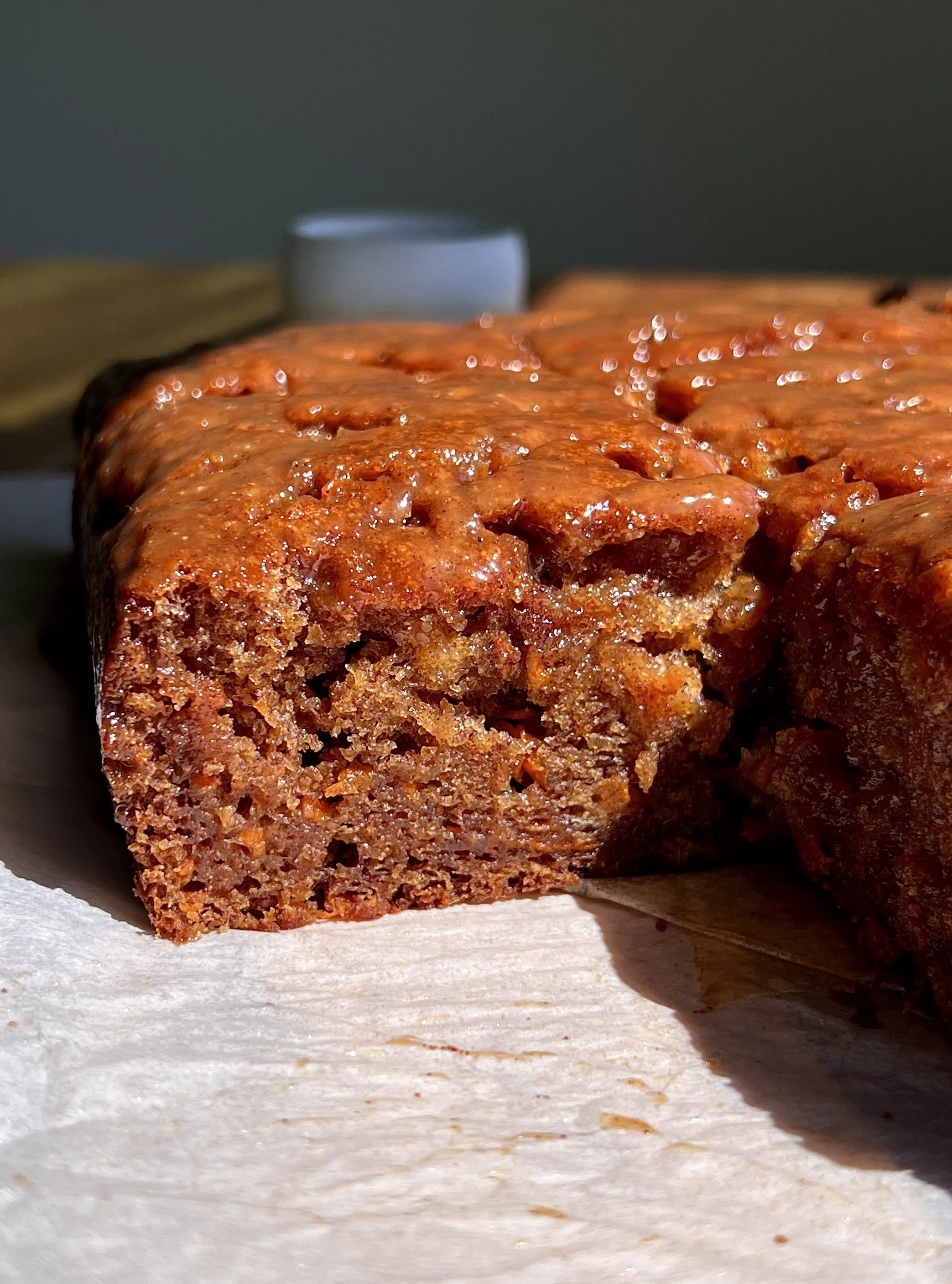 Close-up of carrot cake sticky toffee pudding soaked with spiced toffee sauce melting into the crumb.