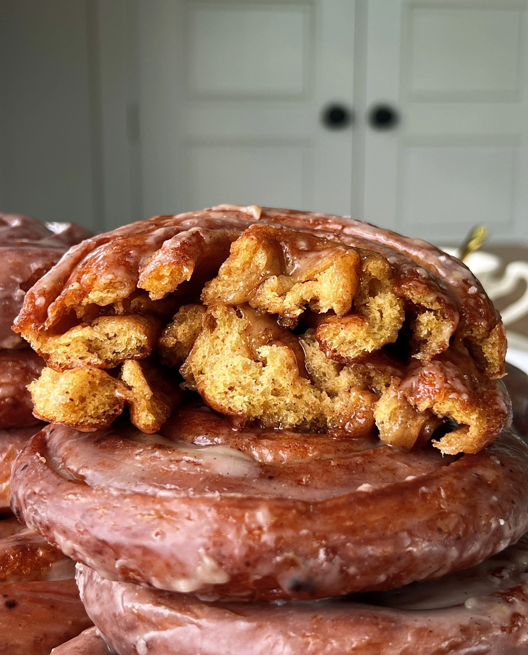Pumpkin spice honey bun pulled apart showing the soft tender pumpkin dough and gooey layers of honey butter and pumpkin spice brown sugar filling inside a golden exterior with honey glaze.