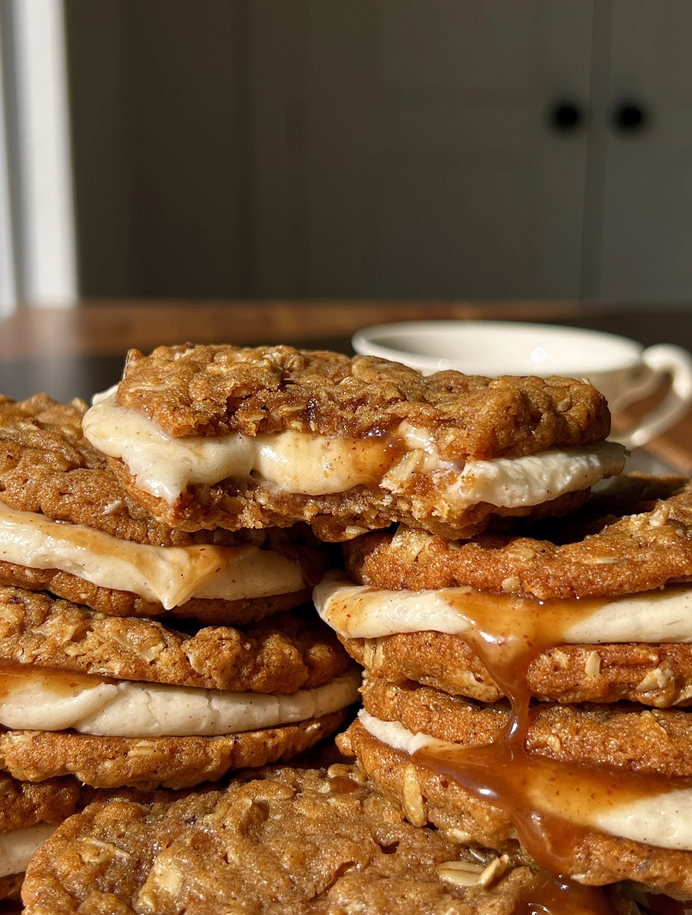 Brown butter sweet potato oatmeal cream pie with a bite taken out showing the soft chewy spiced sweet potato oatmeal cookie and lush brown butter cream cheese filling with salted maple caramel melting inside.