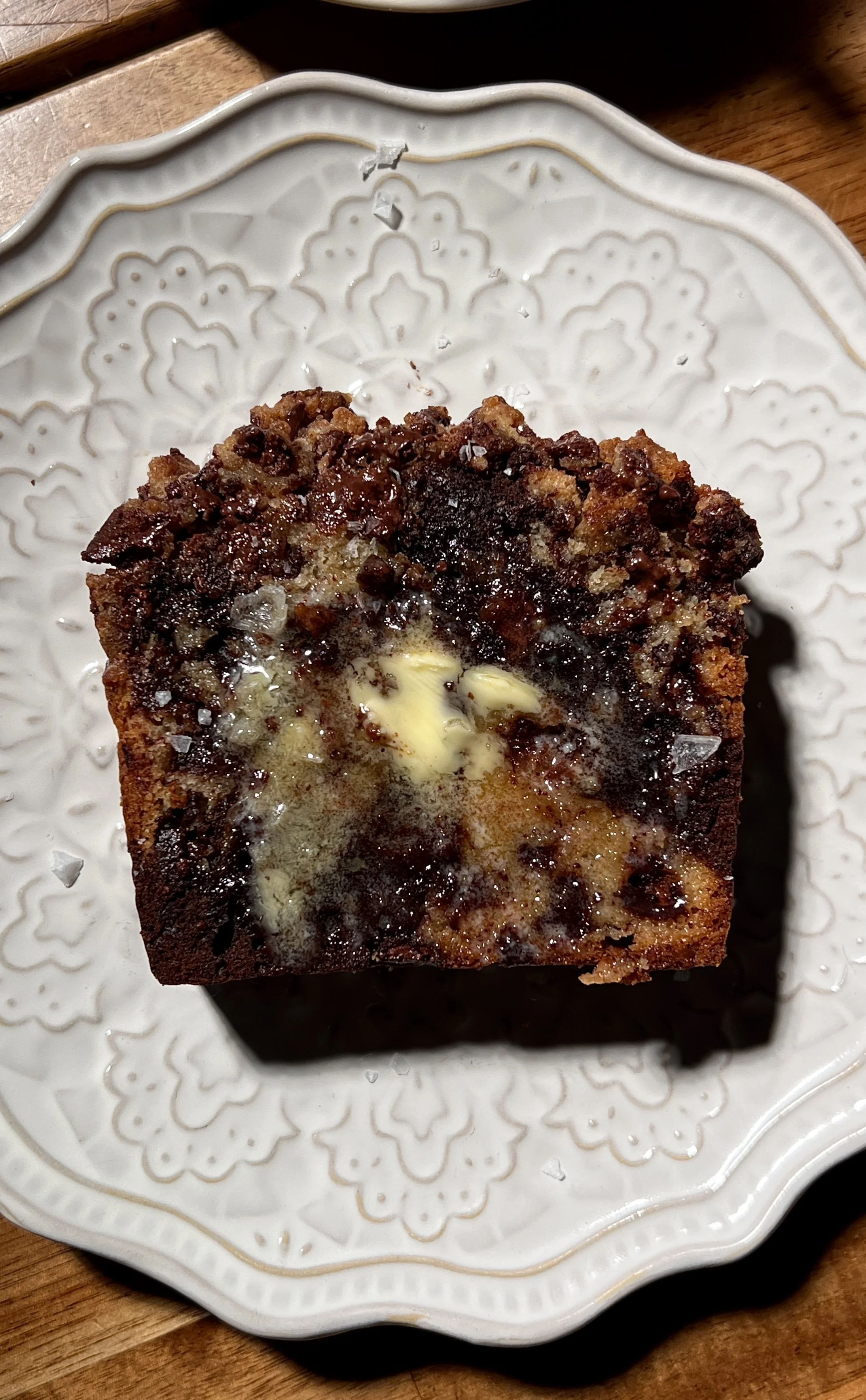 Brown butter marbled chocolate chip crumb loaf cake sliced and served warm, showing vanilla and chocolate swirled crumb, melty chocolate chips, and a buttery crumb topping, finished with flaky sea salt and coffee on the side.