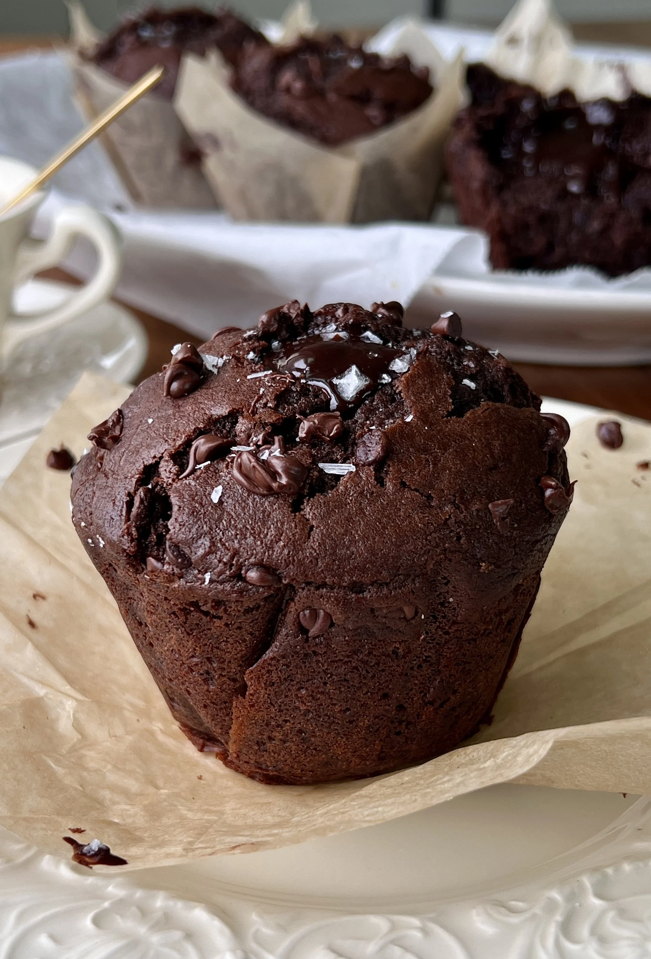 Close-up of a bakery-style triple chocolate fudge muffin with a soft and fluffy crumb, melty chocolate chips throughout, and a molten chocolate ganache center.