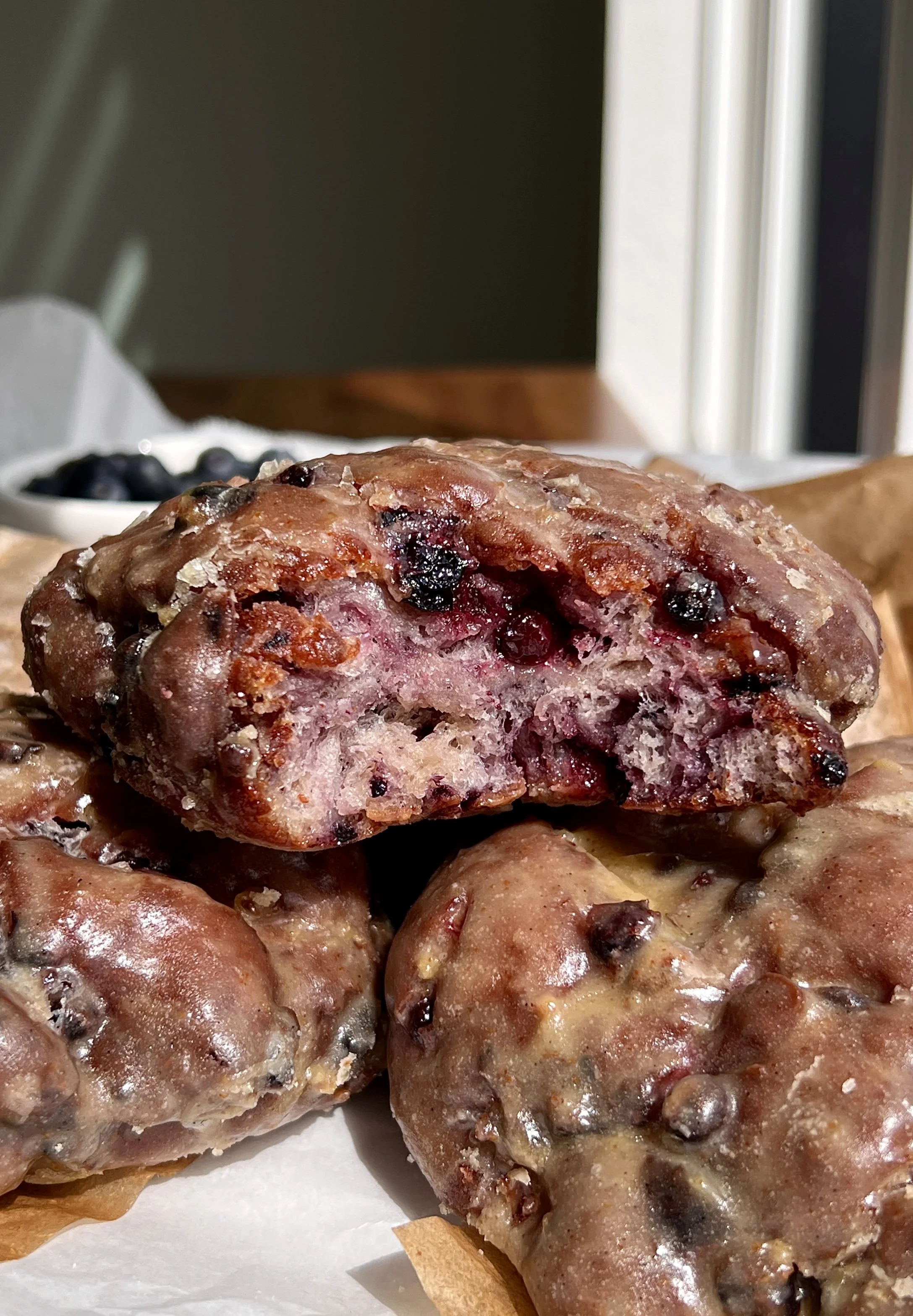 Stack of golden blueberry fritters coated in brown butter lemon glaze served with a hot cup of coffee.