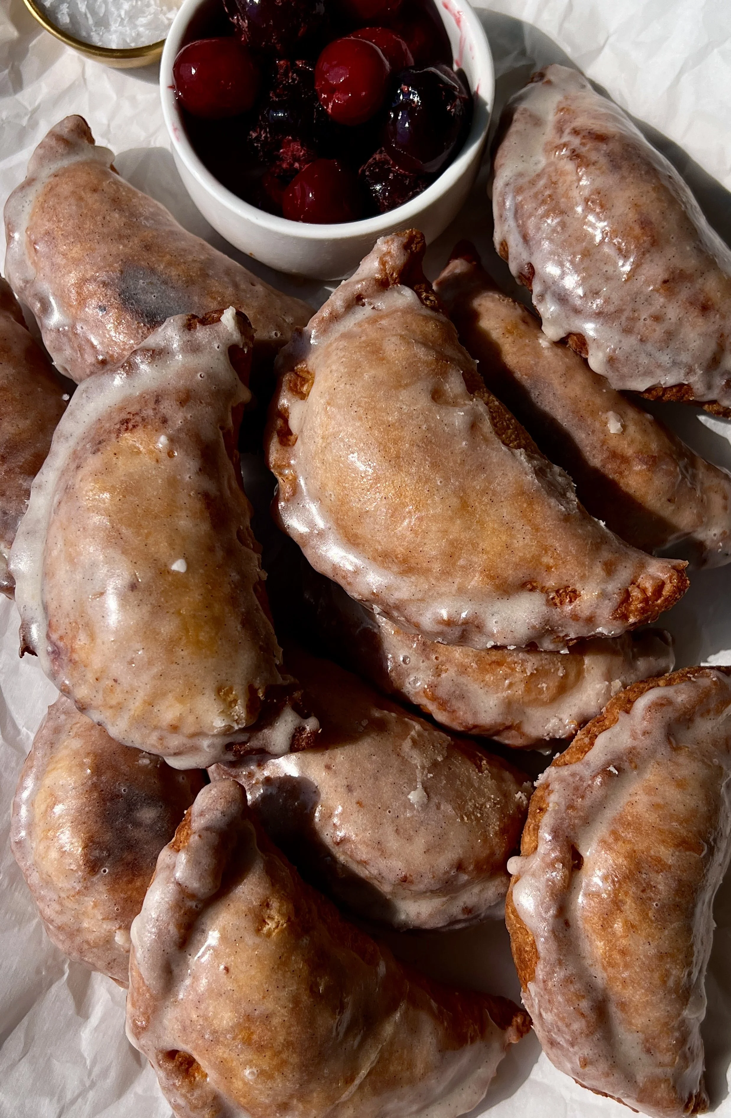 Fried cherry hand pies with a golden flaky buttery crust finished with a vanilla bean glaze melting over the top.