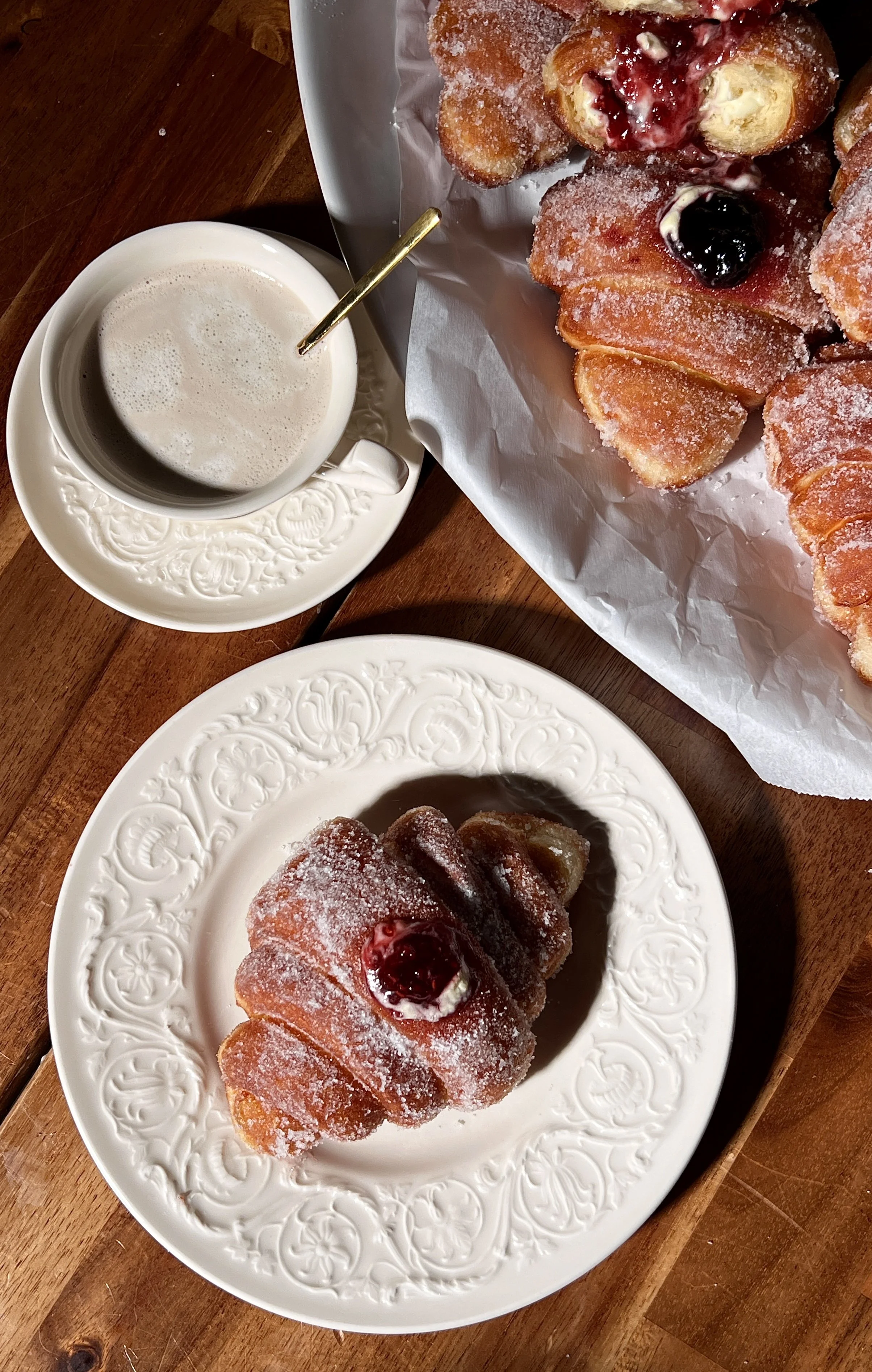 Croissant-shaped doughnuts filled with vanilla bean custard and raspberry jam, rolled in sugar and fried until golden.