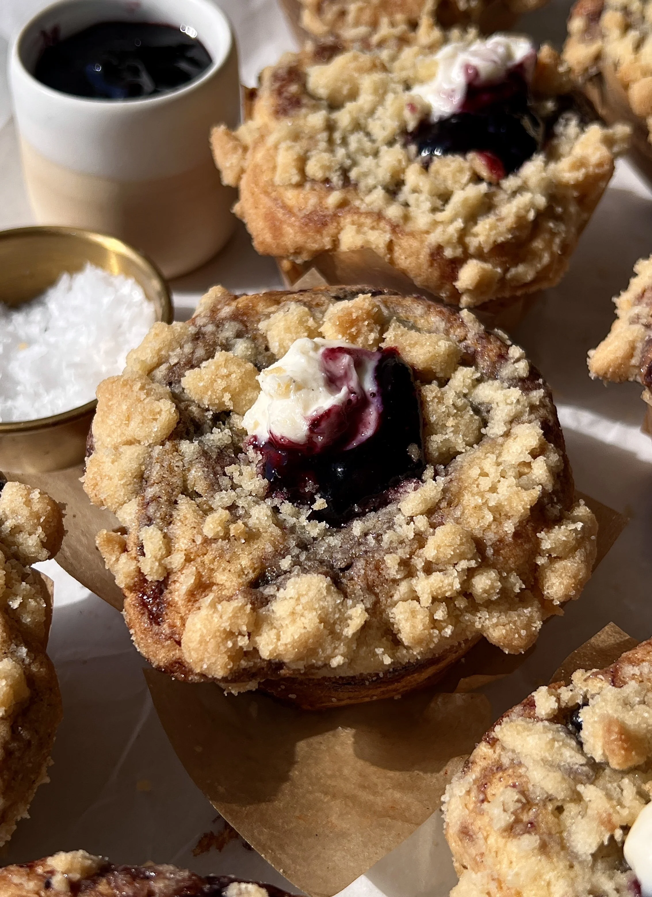 Close-up of a soft and buttery blueberry muffin cheesecake cookie cup with a rich and creamy cheesecake filling and perfectly golden crumble topping throughout.