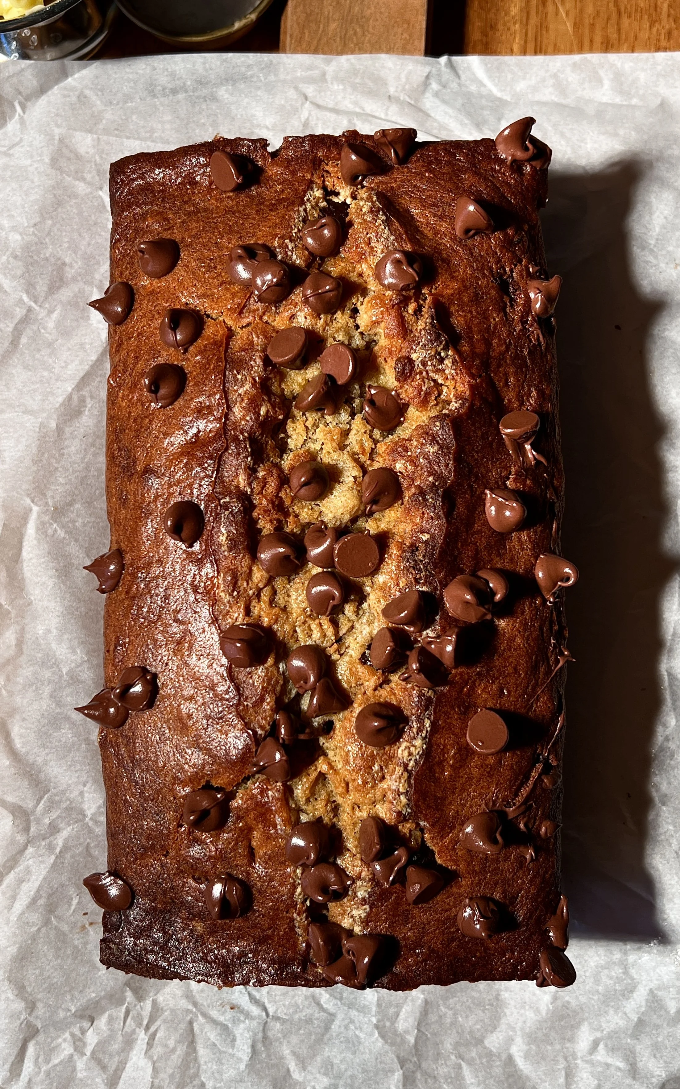 Brown butter banana bread loaf with melty chocolate chips, baked until golden, sliced and served warm with butter, flaky sea salt, and a cup of coffee.
