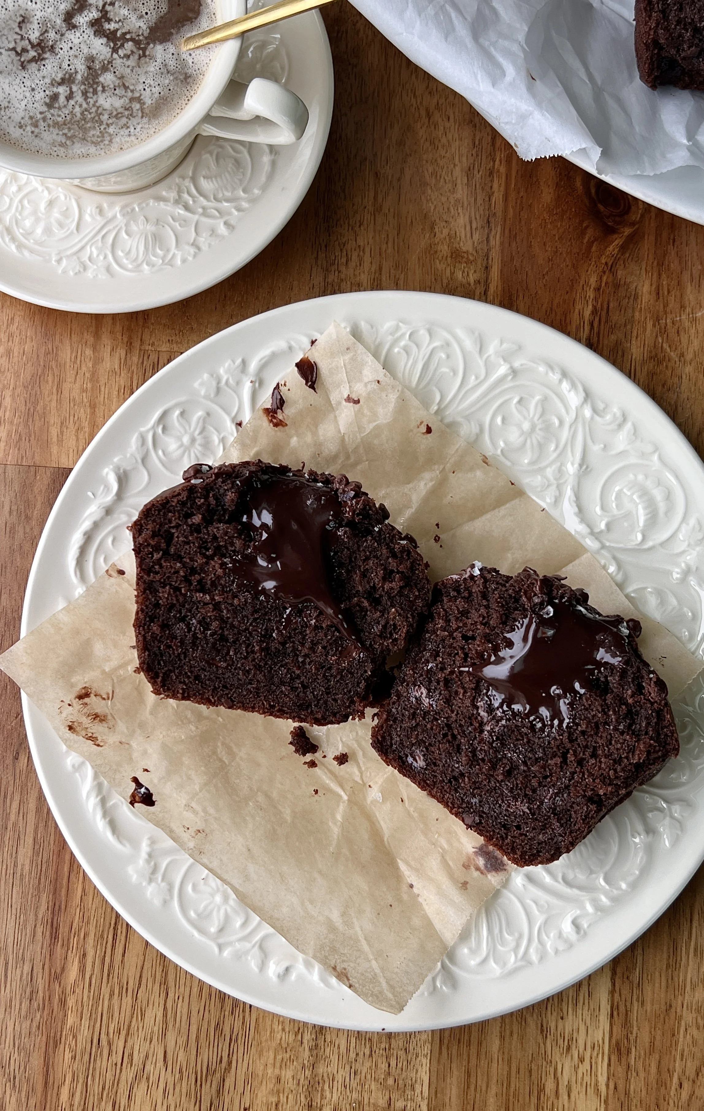 Beyond soft and fluffy bakery-style triple chocolate fudge muffins with a tall domed muffin top, melty chocolate chips throughout, and a molten chocolate ganache center served warm with a hot cup of coffee.