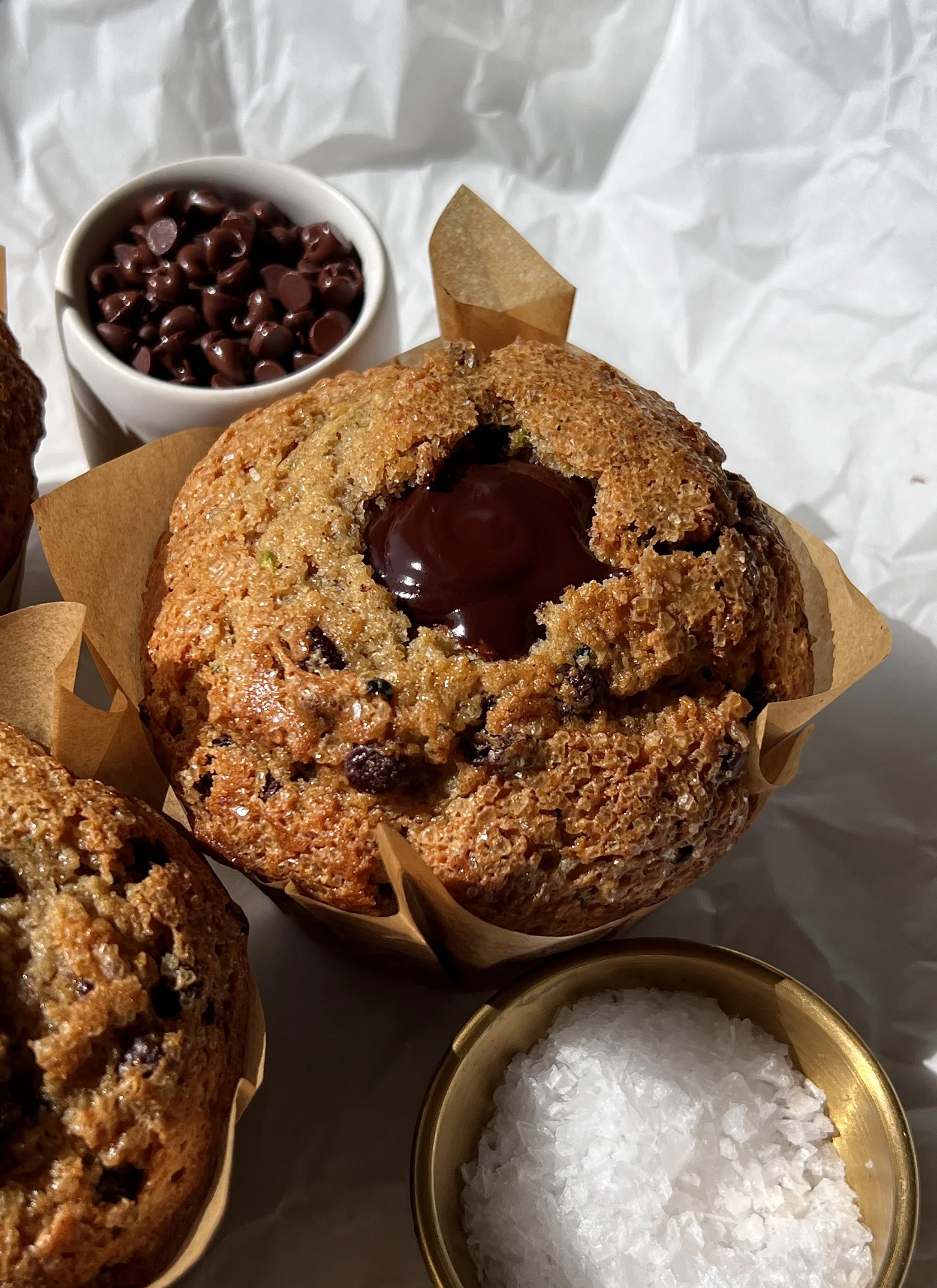 Close-up of a bakery-style chocolate fudge zucchini muffin with a soft and fluffy tender crumb, melty chocolate chips throughout, and a warm molten chocolate ganache center.