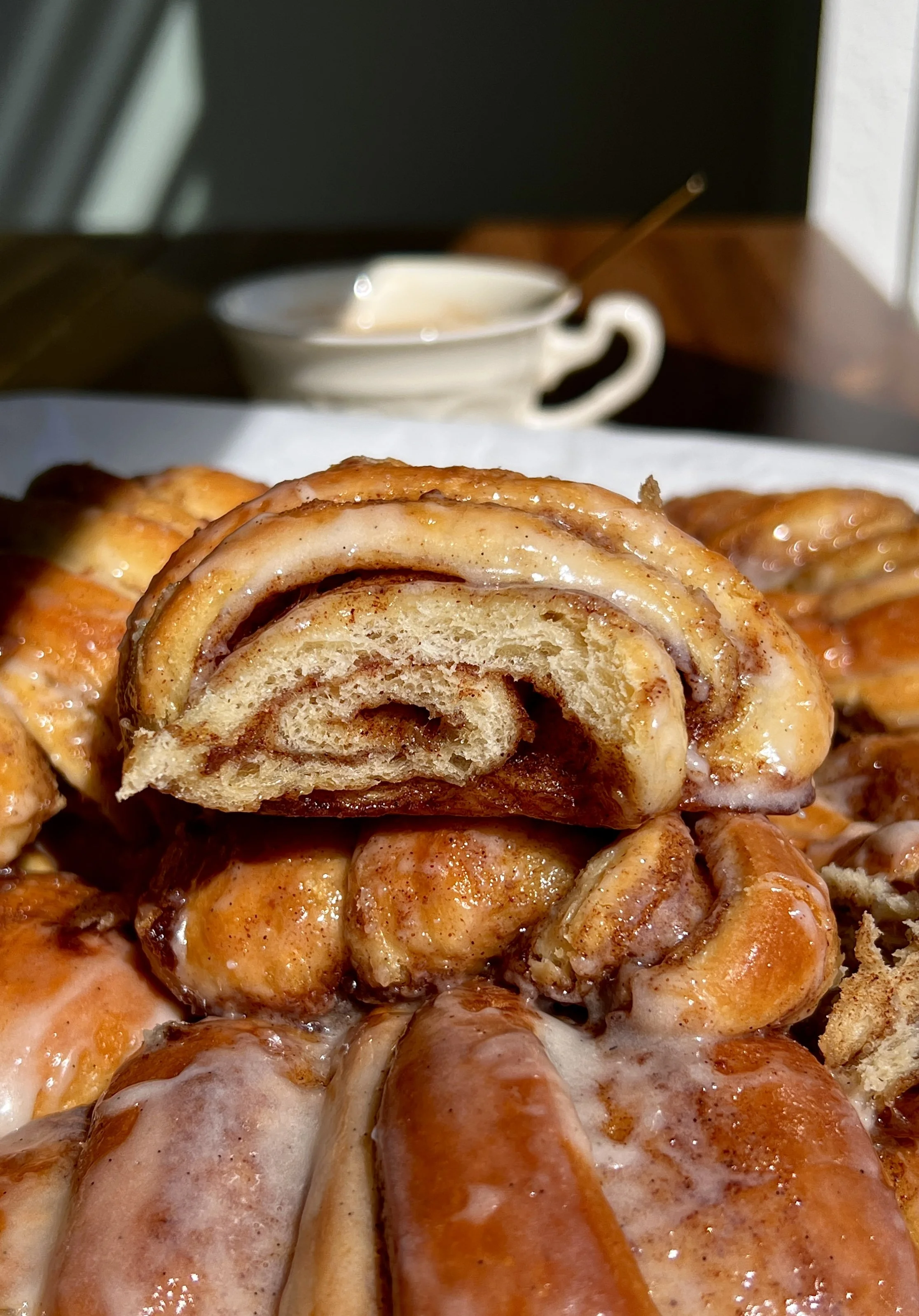 Broken open cinnamon roll croissant showing soft, fluffy layers and melty cinnamon filling.