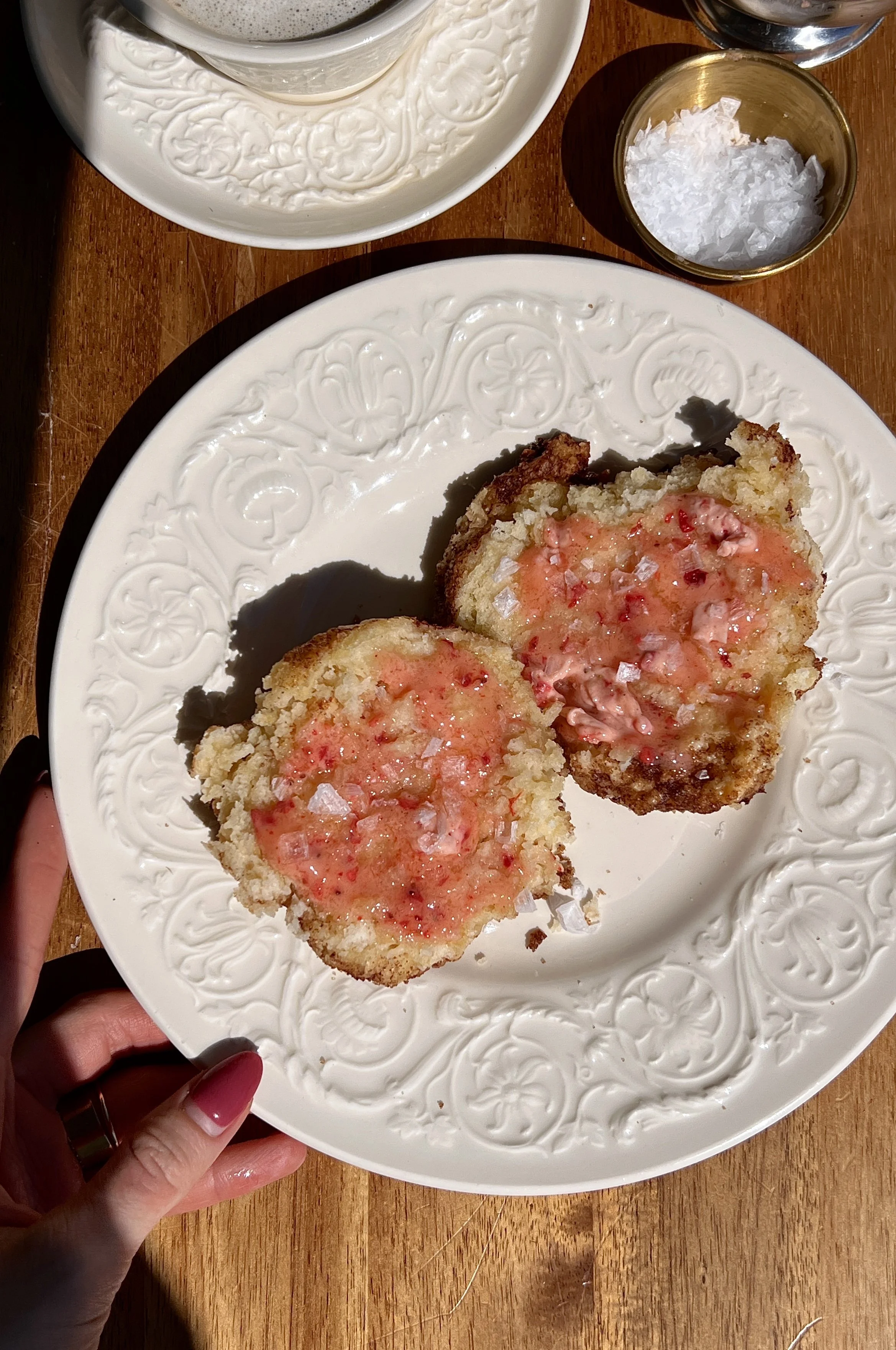 Soft and fluffy cinnamon crunch sourdough cathead biscuits served warm with a generous spread of whipped strawberry honey butter, a sprinkle of flaky sea salt, and a hot cup of coffee.