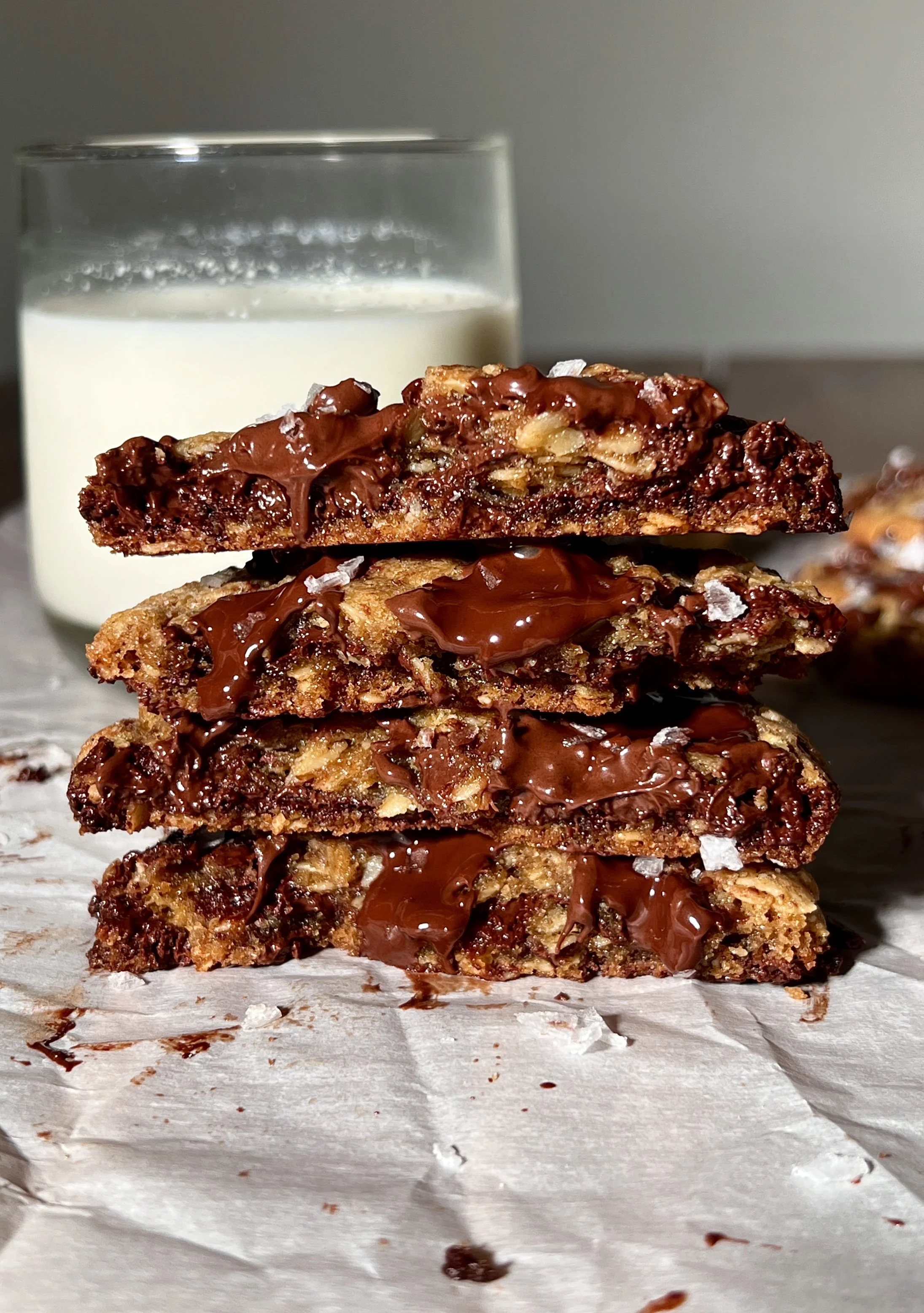 Brown butter oatmeal chocolate chip cookies with crisp golden edges and gooey centers, studded with melty chocolate chips and finished with flaky sea salt, served warm with a glass of milk.