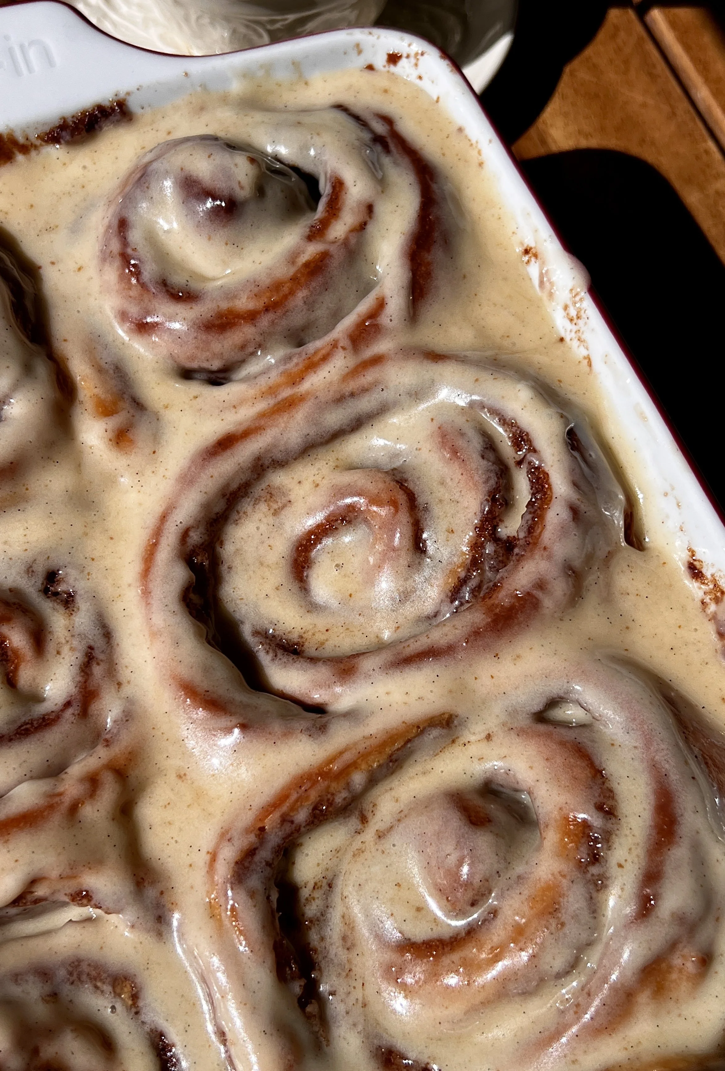 Pan of golden brown butter buttermilk cinnamon rolls with sticky caramelized edges topped with smooth brown butter cream cheese frosting melting into every swirl.