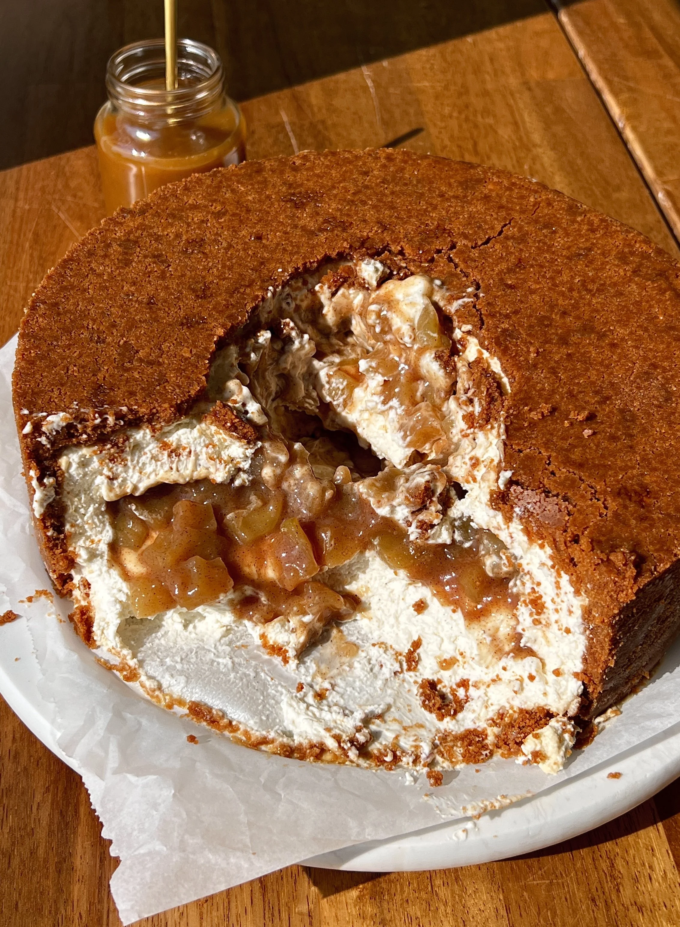 Upside down apple pie cheesecake with a buttery Biscoff cookie crust on top inverted to serve with a brown sugar salted caramel drizzled over.